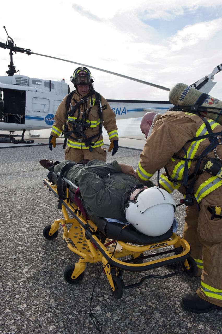 CAPE CANAVERAL, Fla. -- NASA Fire Rescue personnel assist volunteers portraying injured Huey II helicopter crew members participating in the aviation safety exercise during Emergency Response Safety Training at the Shuttle Landing Facility, Runway 33, at NASA’s Kennedy Space Center in Florida.    The simulated helicopter mishap exercise was conducted to evaluate emergency response and mishap investigations of aircraft at Kennedy. Participants included Air Rescue Fire Fighters, Flight Operations, Disaster Preparedness, Security, and Safety. NASA mandates simulated aviation safety training take place every two years. Photo credit: NASA/Kim Shiflett