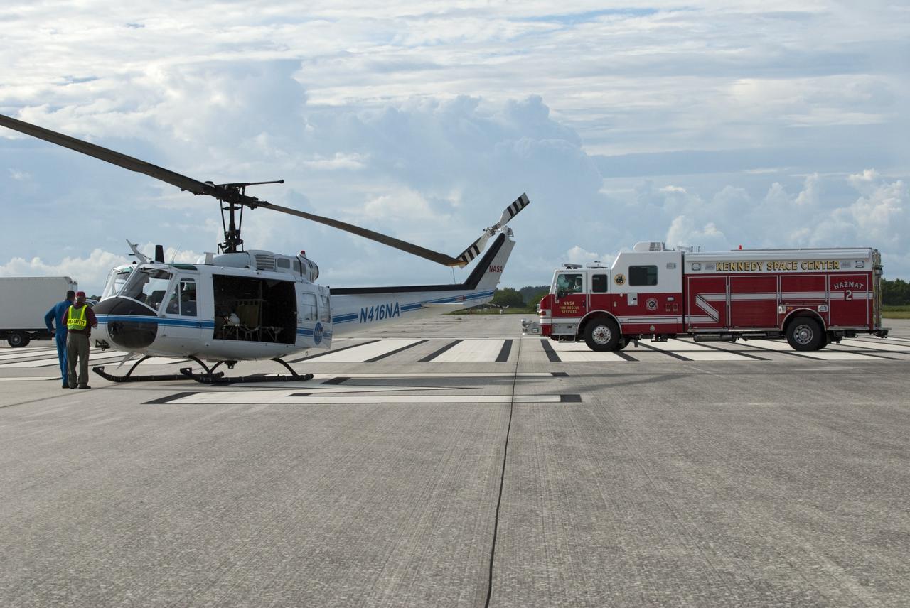 CAPE CANAVERAL, Fla. -- Volunteers, portraying their individual roles, stand beside a NASA Fire Rescue Services vehicle and a Huey II helicopter in support of the aviation safety exercise during Emergency Response Safety Training at the Shuttle Landing Facility, Runway 33, at NASA’s Kennedy Space Center in Florida.    The simulated helicopter mishap exercise was conducted to evaluate emergency response and mishap investigations of aircraft at Kennedy. Participants included Air Rescue Fire Fighters, Flight Operations, Disaster Preparedness, Security, and Safety. NASA mandates simulated aviation safety training take place every two years. Photo credit: NASA/Kim Shiflett