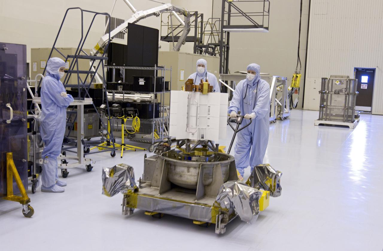 CAPE CANAVERAL, Fla. -- Workers dressed in clean room attire, known as bunny suits, transfer the multi-mission radioisotope thermoelectric generator (MMRTG) for NASA's Mars Science Laboratory (MSL) mission on its holding base from the airlock of the Payload Hazardous Servicing Facility (PHSF) into the facility's high bay. In the high bay, the MMRTG temporarily will be installed on the MSL rover, Curiosity, for a fit check but will be installed on the rover for launch at the pad.    The MMRTG will generate the power needed for the mission from the natural decay of plutonium-238, a non-weapons-grade form of the radioisotope. Heat given off by this natural decay will provide constant power through the day and night during all seasons. Curiosity, MSL's car-sized rover, has 10 science instruments designed to search for signs of life, including methane, and help determine if the gas is from a biological or geological source. Waste heat from the MMRTG will be circulated throughout the rover system to keep instruments, computers, mechanical devices and communications systems within their operating temperature ranges. Launch of MSL aboard a United Launch Alliance Atlas V rocket is planned for Nov. 25 from Space Launch Complex 41 on Cape Canaveral Air Force Station. For more information, visit http://www.nasa.gov/msl. Photo credit: NASA/Cory Huston