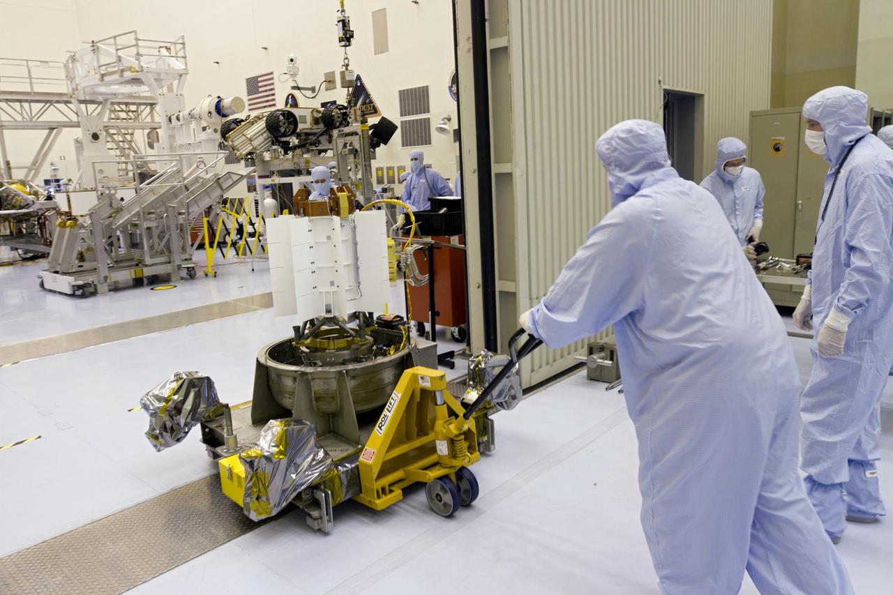 CAPE CANAVERAL, Fla. -- Workers dressed in clean room attire, known as bunny suits, transfer the multi-mission radioisotope thermoelectric generator (MMRTG) for NASA's Mars Science Laboratory (MSL) mission on its holding base through the doors of the airlock of the Payload Hazardous Servicing Facility (PHSF) into the facility's high bay. In the high bay, the MMRTG temporarily will be installed on the MSL rover, Curiosity (in the background, at right), for a fit check using the MMRTG integration cart (in the background, at left). The MMRTG will be installed on the rover for launch at the pad. The MMRTG will generate the power needed for the mission from the natural decay of plutonium-238, a non-weapons-grade form of the radioisotope. Heat given off by this natural decay will provide constant power through the day and night during all seasons. Curiosity, MSL's car-sized rover, has 10 science instruments designed to search for signs of life, including methane, and help determine if the gas is from a biological or geological source. Waste heat from the MMRTG will be circulated throughout the rover system to keep instruments, computers, mechanical devices and communications systems within their operating temperature ranges. Launch of MSL aboard a United Launch Alliance Atlas V rocket is planned for Nov. 25 from Space Launch Complex 41 on Cape Canaveral Air Force Station. For more information, visit http://www.nasa.gov/msl. Photo credit: NASA/Cory Huston
