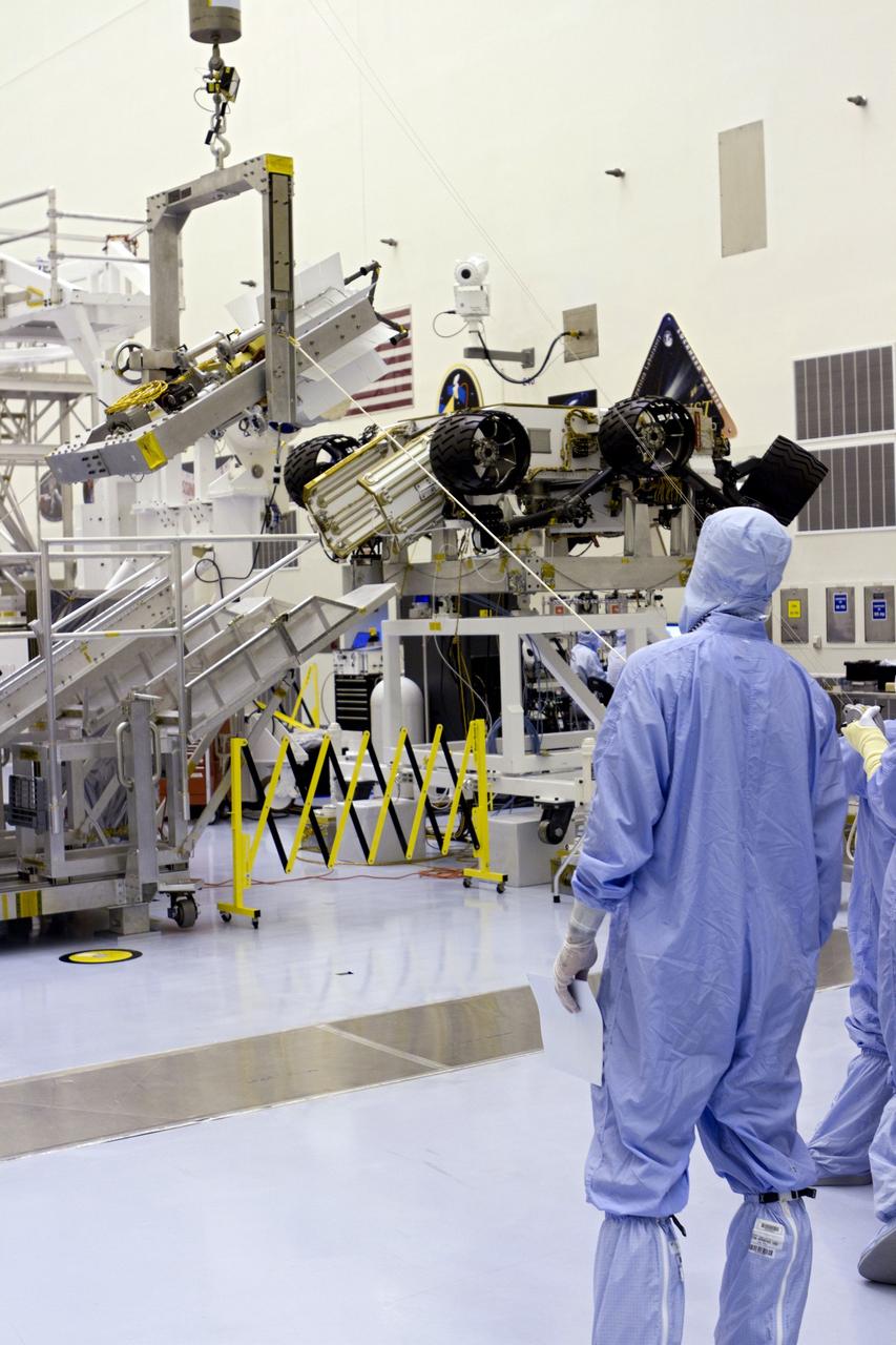 CAPE CANAVERAL, Fla. -- In the high bay of the Payload Hazardous Servicing Facility (PHSF) at NASA's Kennedy Space Center in Florida, spacecraft technicians from NASA's Jet Propulsion Laboratory guide the multi-mission radioisotope thermoelectric generator (MMRTG) for NASA's Mars Science Laboratory (MSL) mission on the turning fixture toward the MMRTG integration cart. The cart will be used to install the MMRTG on the Curiosity rover for a fit check. The rover is on an elevated work stand, at right. The MMRTG will be installed on the rover for launch at the pad.    The MMRTG will generate the power needed for the mission from the natural decay of plutonium-238, a non-weapons-grade form of the radioisotope. Heat given off by this natural decay will provide constant power through the day and night during all seasons. Curiosity, MSL's car-sized rover, has 10 science instruments designed to search for signs of life, including methane, and help determine if the gas is from a biological or geological source. Waste heat from the MMRTG will be circulated throughout the rover system to keep instruments, computers, mechanical devices and communications systems within their operating temperature ranges. Launch of MSL aboard a United Launch Alliance Atlas V rocket is planned for Nov. 25 from Space Launch Complex 41 on Cape Canaveral Air Force Station. For more information, visit http://www.nasa.gov/msl. Photo credit: NASA/Cory Huston