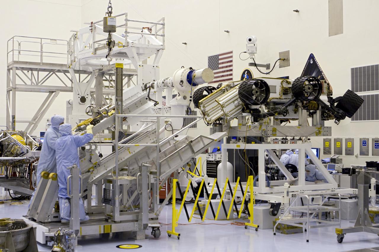 CAPE CANAVERAL, Fla. -- In the high bay of the Payload Hazardous Servicing Facility (PHSF) at NASA's Kennedy Space Center in Florida, the multi-mission radioisotope thermoelectric generator (MMRTG) for NASA's Mars Science Laboratory (MSL) mission on the turning fixture is lowered onto the MMRTG integration cart. The cart will be used to install the MMRTG on the Curiosity rover for a fit check. The rover is on an elevated work stand, at right. The MMRTG will be installed on the rover for launch at the pad.    The MMRTG will generate the power needed for the mission from the natural decay of plutonium-238, a non-weapons-grade form of the radioisotope. Heat given off by this natural decay will provide constant power through the day and night during all seasons. Curiosity, MSL's car-sized rover, has 10 science instruments designed to search for signs of life, including methane, and help determine if the gas is from a biological or geological source. Waste heat from the MMRTG will be circulated throughout the rover system to keep instruments, computers, mechanical devices and communications systems within their operating temperature ranges. Launch of MSL aboard a United Launch Alliance Atlas V rocket is planned for Nov. 25 from Space Launch Complex 41 on Cape Canaveral Air Force Station. For more information, visit http://www.nasa.gov/msl. Photo credit: NASA/Cory Huston
