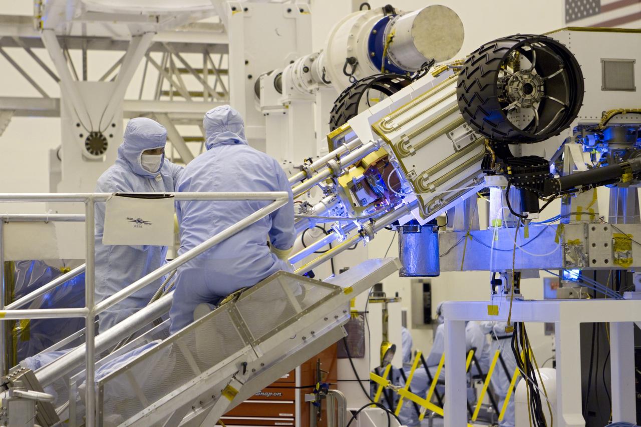 CAPE CANAVERAL, Fla. -- In the high bay of the Payload Hazardous Servicing Facility (PHSF) at NASA's Kennedy Space Center in Florida, spacecraft technicians from NASA's Jet Propulsion Laboratory use extension tools to attach the multi-mission radioisotope thermoelectric generator (MMRTG) for NASA's Mars Science Laboratory (MSL) mission on the MMRTG integration cart onto the aft of the Curiosity rover for a fit check. The MMRTG then will be removed and installed on the rover for launch at the pad.    The MMRTG will generate the power needed for the mission from the natural decay of plutonium-238, a non-weapons-grade form of the radioisotope. Heat given off by this natural decay will provide constant power through the day and night during all seasons. Curiosity, MSL's car-sized rover, has 10 science instruments designed to search for signs of life, including methane, and help determine if the gas is from a biological or geological source. Waste heat from the MMRTG will be circulated throughout the rover system to keep instruments, computers, mechanical devices and communications systems within their operating temperature ranges. Launch of MSL aboard a United Launch Alliance Atlas V rocket is planned for Nov. 25 from Space Launch Complex 41 on Cape Canaveral Air Force Station. For more information, visit http://www.nasa.gov/msl. Photo credit: NASA/Cory Huston