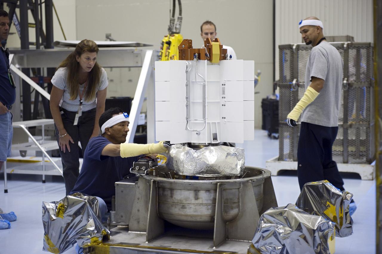 CAPE CANAVERAL, Fla. -- In the airlock of the Payload Hazardous Servicing Facility at NASA's Kennedy Space Center in Florida, Department of Energy employees prepare the support base of the multi-mission radioisotope thermoelectric generator (MMRTG) for NASA's Mars Science Laboratory (MSL) mission for installation of the mesh container, known as the "gorilla cage." The cage, in the background at right, protects the MMRTG during transport and allows any excess heat generated to dissipate into the air. Transport of the MMRTG to the RTG storage facility follows the completion of the MMRTG fit check on the Curiosity rover. The MMRTG will generate the power needed for the mission from the natural decay of plutonium-238, a non-weapons-grade form of the radioisotope. Heat given off by this natural decay will provide constant power through the day and night during all seasons. MSL's components include a car-sized rover, Curiosity, which has 10 science instruments designed to search for signs of life, including methane, and help determine if the gas is from a biological or geological source. Waste heat from the MMRTG will be circulated throughout the rover system to keep instruments, computers, mechanical devices and communications systems within their operating temperature ranges. Launch of MSL aboard a United Launch Alliance Atlas V rocket is targeted for Nov. 25 from Space Launch Complex 41 on Cape Canaveral Air Force Station. For more information, visit http://www.nasa.gov/msl. Photo credit: NASA/Kim Shiflett