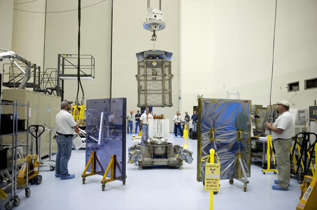 CAPE CANAVERAL, Fla. -- In the airlock of the Payload Hazardous Servicing Facility at NASA's Kennedy Space Center in Florida, Department of Energy employees lower the mesh container, known as the "gorilla cage," toward the multi-mission radioisotope thermoelectric generator (MMRTG) for NASA's Mars Science Laboratory (MSL) mission. The employees are standing behind mobile plexiglass radiation shields to help minimize the employees' radiation exposure. The cage protects the MMRTG during transport and allows any excess heat generated to dissipate into the air. Transport of the MMRTG to the RTG storage facility follows the completion of the MMRTG fit check on the Curiosity rover.     The MMRTG will generate the power needed for the mission from the natural decay of plutonium-238, a non-weapons-grade form of the radioisotope. Heat given off by this natural decay will provide constant power through the day and night during all seasons. MSL's components include a car-sized rover, Curiosity, which has 10 science instruments designed to search for signs of life, including methane, and help determine if the gas is from a biological or geological source. Waste heat from the MMRTG will be circulated throughout the rover system to keep instruments, computers, mechanical devices and communications systems within their operating temperature ranges. Launch of MSL aboard a United Launch Alliance Atlas V rocket is targeted for Nov. 25 from Space Launch Complex 41 on Cape Canaveral Air Force Station. For more information, visit http://www.nasa.gov/msl. Photo credit: NASA/Kim Shiflett