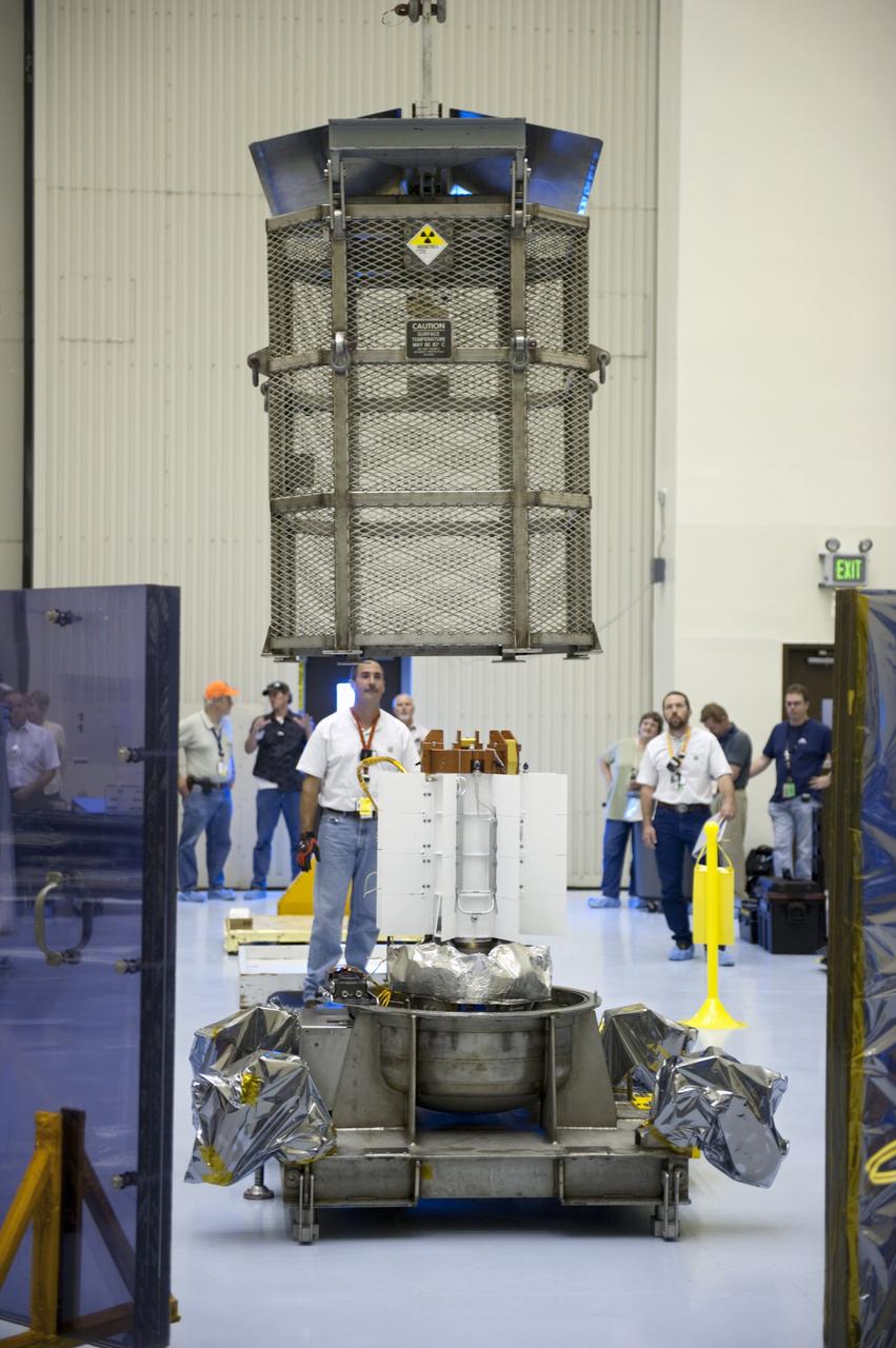 CAPE CANAVERAL, Fla. -- In the airlock of the Payload Hazardous Servicing Facility at NASA's Kennedy Space Center in Florida, Department of Energy employees lower the mesh container, known as the "gorilla cage," toward the multi-mission radioisotope thermoelectric generator (MMRTG) for NASA's Mars Science Laboratory (MSL) mission. The mobile plexiglass radiation shields in the foreground help minimize the employees' radiation exposure. The cage protects the MMRTG during transport and allows any excess heat generated to dissipate into the air. Transport of the MMRTG to the RTG storage facility follows the completion of the MMRTG fit check on the Curiosity rover.     The MMRTG will generate the power needed for the mission from the natural decay of plutonium-238, a non-weapons-grade form of the radioisotope. Heat given off by this natural decay will provide constant power through the day and night during all seasons. MSL's components include a car-sized rover, Curiosity, which has 10 science instruments designed to search for signs of life, including methane, and help determine if the gas is from a biological or geological source. Waste heat from the MMRTG will be circulated throughout the rover system to keep instruments, computers, mechanical devices and communications systems within their operating temperature ranges. Launch of MSL aboard a United Launch Alliance Atlas V rocket is targeted for Nov. 25 from Space Launch Complex 41 on Cape Canaveral Air Force Station. For more information, visit http://www.nasa.gov/msl. Photo credit: NASA/Kim Shiflett