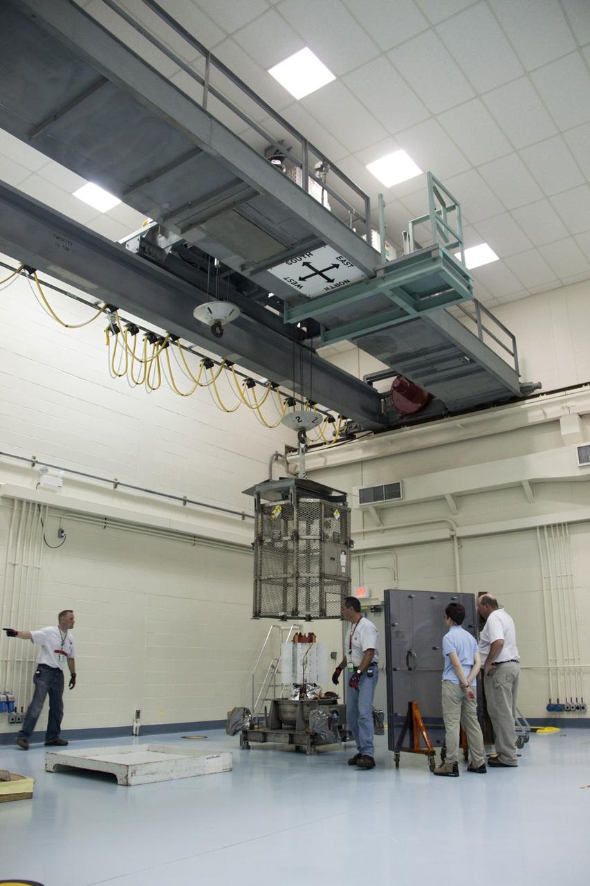 CAPE CANAVERAL, Fla. -- In the high bay of the RTG storage facility (RTGF) at NASA's Kennedy Space Center in Florida, the mesh container enclosing the multi-mission radioisotope thermoelectric generator (MMRTG) for NASA's Mars Science Laboratory (MSL) mission is lifted from around the MMRTG. The container, known as the "gorilla cage," protects the MMRTG during transport and allows any excess heat generated to dissipate into the air.  The cage is being removed following the return of the MMRTG to the RTGF from a fit check on MSL's Curiosity rover in the Payload Hazardous Servicing Facility (PHSF).  The workers at right are observing the operation from behind a mobile plexiglass radiation shield to minimize their radiation exposure.    The MMRTG will generate the power needed for the mission from the natural decay of plutonium-238, a non-weapons-grade form of the radioisotope. Heat given off by this natural decay will provide constant power through the day and night during all seasons. MSL's components include a compact car-sized rover, Curiosity, which has 10 science instruments designed to search for signs of life, including methane, and help determine if the gas is from a biological or geological source. Waste heat from the MMRTG will be circulated throughout the rover system to keep instruments, computers, mechanical devices and communications systems within their operating temperature ranges. Launch of MSL aboard a United Launch Alliance Atlas V rocket is targeted for Nov. 25 from Space Launch Complex 41 on Cape Canaveral Air Force Station. For more information, visit http://www.nasa.gov/msl. Photo credit: NASA/Troy Cryder