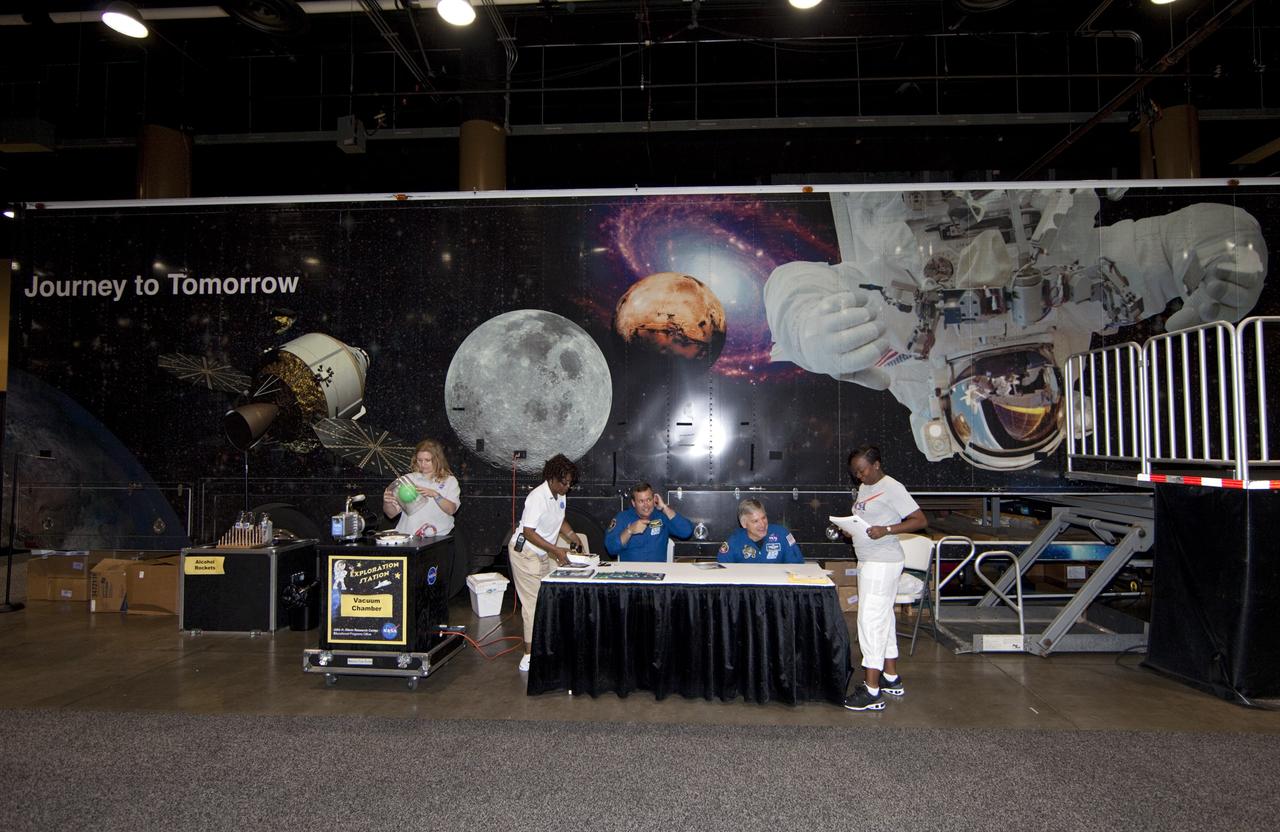 CAPE CANAVERAL, Fla. -- NASA astronauts Mike Foreman (seated, left) and Greg Johnson (seated, right) enjoy the quiet before the storm as they prepare to sign autographs for the nationwide attendees of the Tom Joyner Family Reunion. They are seated in front of NASA’s Journey to Tomorrow trailer at reunion headquarters at the Gaylord Palms Resort and Convention Center in Kissimmee, Fla. The reunion was hosted by nationally syndicated radio personality Tom Joyner during the extended Labor Day weekend Sept. 1-4. Besides offering attendees the opportunity to visit tourist attractions in the Orlando area, the reunion gave NASA education specialists an avenue to tout the benefits of math and scientific learning, as well as the many educational opportunities offered by the space agency. For more information on NASA's education initiatives, visit http://www.nasa.gov/education. Photo credit: NASA/Frankie Martin