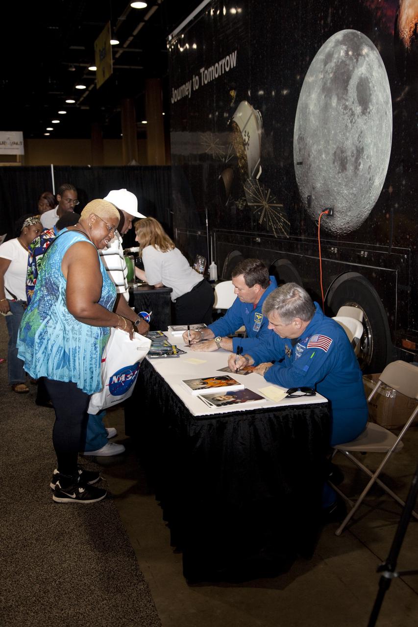 CAPE CANAVERAL, Fla. -- NASA astronauts Mike Foreman (seated, left) and Greg Johnson (seated, right) sign autographs for the nationwide attendees of the Tom Joyner Family Reunion. They are seated in front of NASA’s Journey to Tomorrow trailer at reunion headquarters at the Gaylord Palms Resort and Convention Center in Kissimmee, Fla. The reunion was hosted by nationally syndicated radio personality Tom Joyner during the extended Labor Day weekend Sept. 1-4. Besides offering attendees the opportunity to visit tourist attractions in the Orlando area, the reunion gave NASA education specialists an avenue to tout the benefits of math and scientific learning, as well as the many educational opportunities offered by the space agency. For more information on NASA's education initiatives, visit http://www.nasa.gov/education. Photo credit: NASA/Frankie Martin