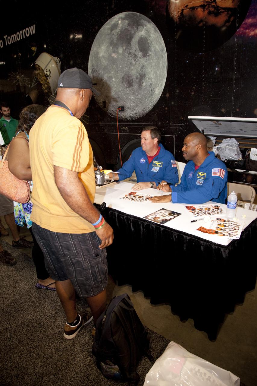 CAPE CANAVERAL, Fla. -- NASA astronauts Mike Foreman (seated, left) and Leland Melvin (seated, right) sign autographs for the nationwide attendees of the Tom Joyner Family Reunion. Melvin also is NASA's associate administrator for education. They are seated in front of NASA’s Journey to Tomorrow trailer at reunion headquarters at the Gaylord Palms Resort and Convention Center in Kissimmee, Fla. The reunion was hosted by nationally syndicated radio personality Tom Joyner during the extended Labor Day weekend Sept. 1-4. Besides offering attendees the opportunity to visit tourist attractions in the Orlando area, the reunion gave NASA education specialists an avenue to tout the benefits of math and scientific learning, as well as the many educational opportunities offered by the space agency. For more information on NASA's education initiatives, visit http://www.nasa.gov/education. Photo credit: NASA/Frankie Martin