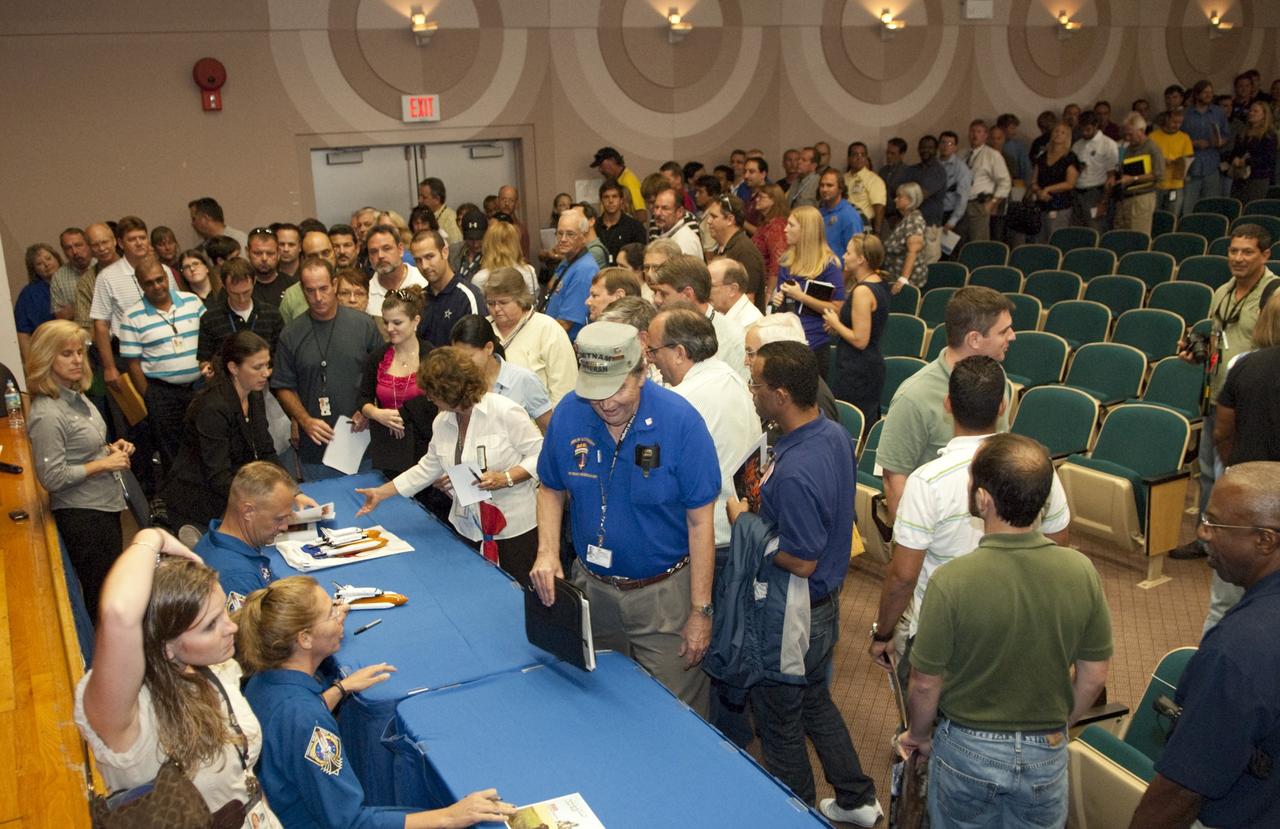 CAPE CANAVERAL, Fla. – Astronauts from Space Shuttle Atlantis’ STS-135 mission return to the Training Auditorium at NASA’s Kennedy Space Center for the traditional post-flight crew return presentation. Crew members autograph mementos for attendees following a presentation about the astronauts' experiences on the mission. Seated from left are Mission Specialist Sandra Magnus and Pilot Doug Hurley.    STS-135 Mission Specialist Rex Walheim was unable to attend the Kennedy event. In July 2011, Atlantis and its crew delivered to the International Space Station the Raffaello multi-purpose logistics module packed with more than 9,400 pounds of spare parts, equipment and supplies that will sustain station operations for the next year. STS-135 was the 33rd and final flight for Atlantis and the final mission of the Space Shuttle Program. For more information, visit www.nasa.gov/mission_pages/shuttle/shuttlemissions/sts135/index.html. Photo credit: NASA/Jim Grossmann