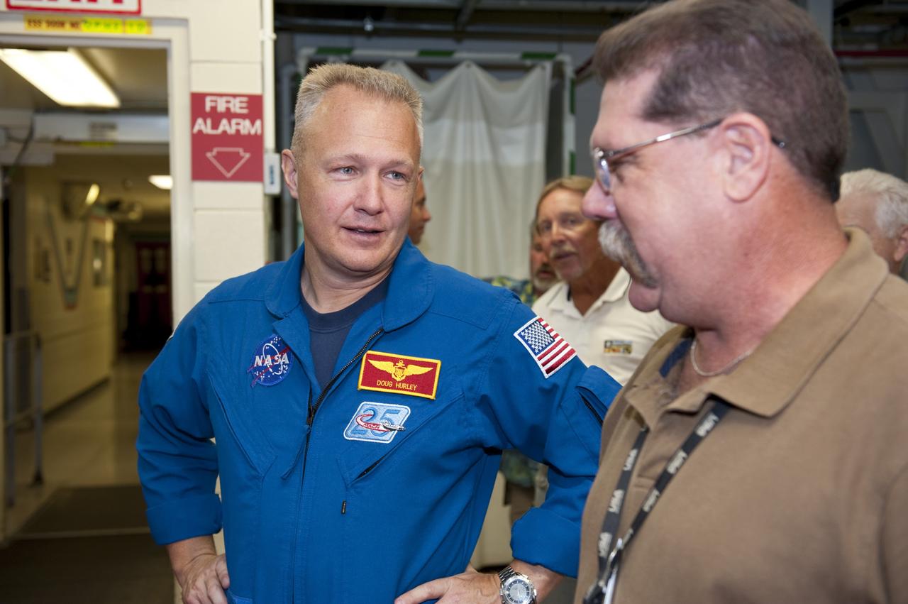 CAPE CANAVERAL, Fla. – STS-135 Pilot Doug Hurley visits with an employee inside Kennedy Space Center's Orbiter Processing Facility-2, where space shuttle Atlantis is being prepared for eventual display at the Kennedy Space Center Visitor Complex in Florida. Hurley, along with Commander Chris Ferguson and Mission Specialist Sandra Magnus, was at the center for the traditional post-flight crew return presentation.      STS-135 Mission Specialist Rex Walheim was unable to attend the Kennedy event. In July 2011, Atlantis and its crew delivered to the International Space Station the Raffaello multi-purpose logistics module packed with more than 9,400 pounds of spare parts, equipment and supplies that will sustain station operations for the next year. STS-135 was the 33rd and final flight for Atlantis and the final mission of the Space Shuttle Program. For more information, visit www.nasa.gov/mission_pages/shuttle/shuttlemissions/sts135/index.html. Photo credit: NASA/Kim Shiflett