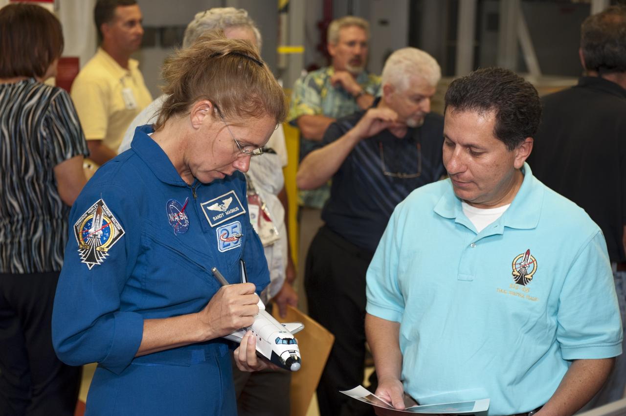 CAPE CANAVERAL, Fla. – STS-135 Mission Specialist Sandra Magnus autographs a space shuttle replica for an employee inside Kennedy Space Center's Orbiter Processing Facility-2, where space shuttle Atlantis is being prepared for eventual display at the Kennedy Space Center Visitor Complex in Florida. Magnus, along with Commander Chris Ferguson and Pilot Doug Hurley, was at the center for the traditional post-flight crew return presentation.     STS-135 Mission Specialist Rex Walheim was unable to attend the Kennedy event. In July 2011, Atlantis and its crew delivered to the International Space Station the Raffaello multi-purpose logistics module packed with more than 9,400 pounds of spare parts, equipment and supplies that will sustain station operations for the next year. STS-135 was the 33rd and final flight for Atlantis and the final mission of the Space Shuttle Program. For more information, visit www.nasa.gov/mission_pages/shuttle/shuttlemissions/sts135/index.html. Photo credit: NASA/Kim Shiflett