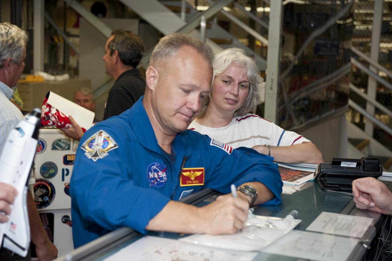 CAPE CANAVERAL, Fla. – STS-135 Pilot Doug Hurley signs an autograph for an employee inside Kennedy Space Center's Orbiter Processing Facility-2, where space shuttle Atlantis is being prepared for eventual display at the Kennedy Space Center Visitor Complex in Florida. Hurley, along with Commander Chris Ferguson and Mission Specialist Sandra Magnus, was at the center for the traditional post-flight crew return presentation.      STS-135 Mission Specialist Rex Walheim was unable to attend the Kennedy event. In July 2011, Atlantis and its crew delivered to the International Space Station the Raffaello multi-purpose logistics module packed with more than 9,400 pounds of spare parts, equipment and supplies that will sustain station operations for the next year. STS-135 was the 33rd and final flight for Atlantis and the final mission of the Space Shuttle Program. For more information, visit www.nasa.gov/mission_pages/shuttle/shuttlemissions/sts135/index.html. Photo credit: NASA/Kim Shiflett