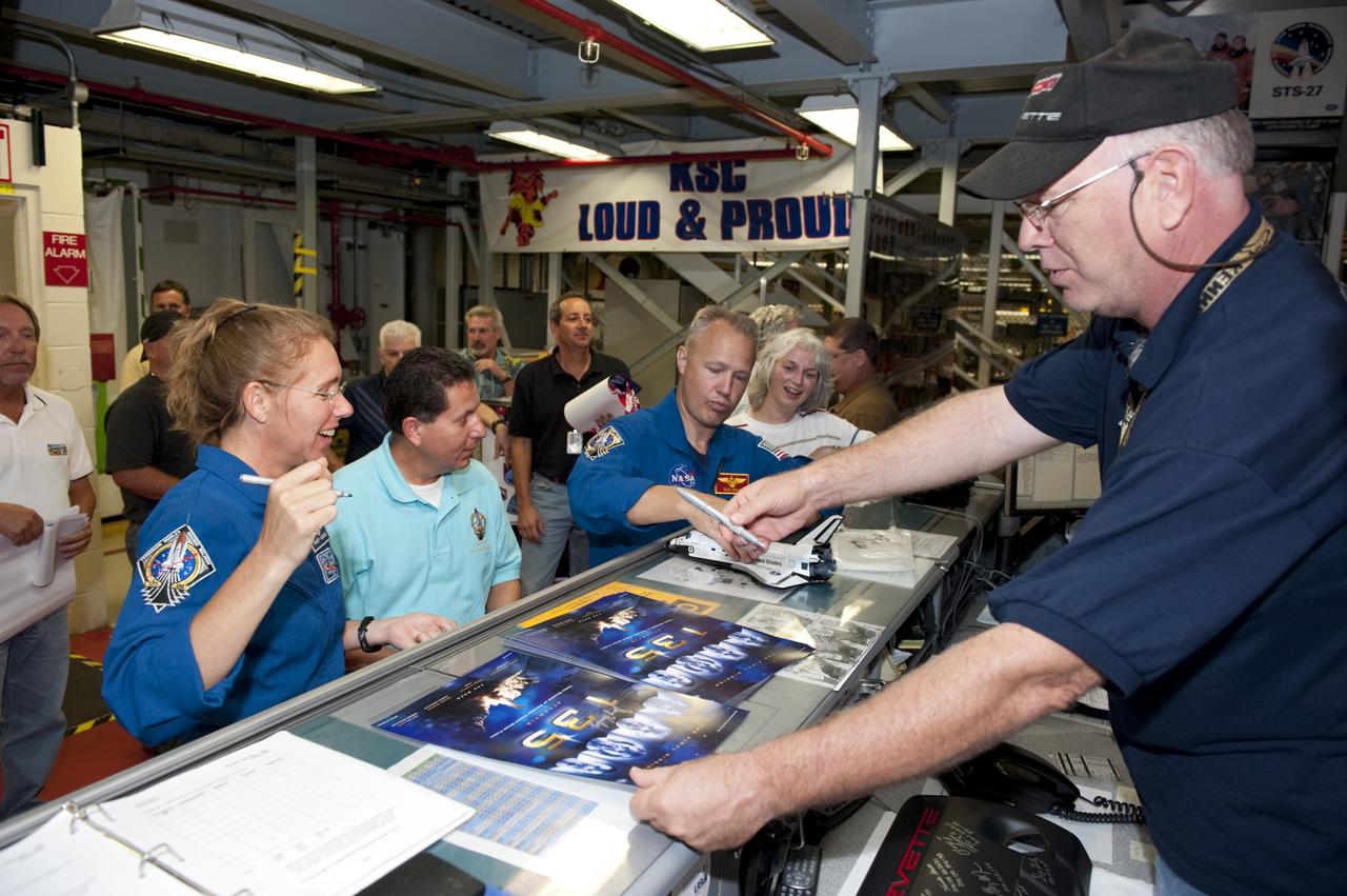 CAPE CANAVERAL, Fla. – STS-135 Mission Specialist Sandra Magnus signs an autograph while Pilot Doug Hurley autographs a space shuttle replica for employees inside Kennedy Space Center's Orbiter Processing Facility-2, where space shuttle Atlantis is being prepared for eventual display at the Kennedy Space Center Visitor Complex in Florida. The astronauts, along with Commander Chris Ferguson, were at the center for the traditional post-flight crew return presentation.     STS-135 Mission Specialist Rex Walheim was unable to attend the Kennedy event. In July 2011, Atlantis and its crew delivered to the International Space Station the Raffaello multi-purpose logistics module packed with more than 9,400 pounds of spare parts, equipment and supplies that will sustain station operations for the next year. STS-135 was the 33rd and final flight for Atlantis and the final mission of the Space Shuttle Program. For more information, visit www.nasa.gov/mission_pages/shuttle/shuttlemissions/sts135/index.html. Photo credit: NASA/Kim Shiflett