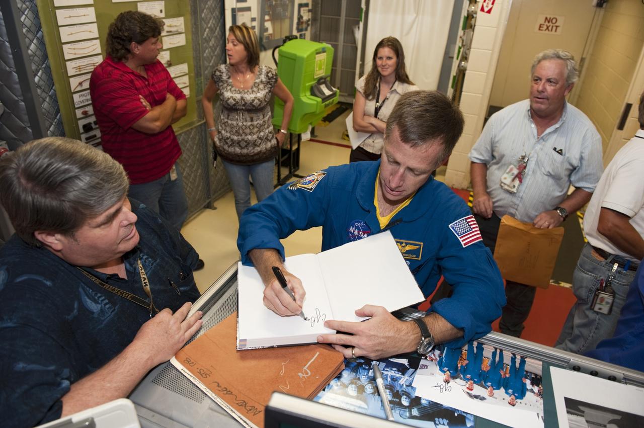 CAPE CANAVERAL, Fla. – STS-135 Commander Chris Ferguson autographs a book for an employee inside Kennedy Space Center's Orbiter Processing Facility-2, where space shuttle Atlantis is being prepared for eventual display at the Kennedy Space Center Visitor Complex in Florida. Ferguson, along Pilot Doug Hurley and Mission Specialist Sandra Magnus, was at the center for the traditional post-flight crew return presentation.     STS-135 Mission Specialist Rex Walheim was unable to attend the Kennedy event. In July 2011, Atlantis and its crew delivered to the International Space Station the Raffaello multi-purpose logistics module packed with more than 9,400 pounds of spare parts, equipment and supplies that will sustain station operations for the next year. STS-135 was the 33rd and final flight for Atlantis and the final mission of the Space Shuttle Program. For more information, visit www.nasa.gov/mission_pages/shuttle/shuttlemissions/sts135/index.html. Photo credit: NASA/Kim Shiflett