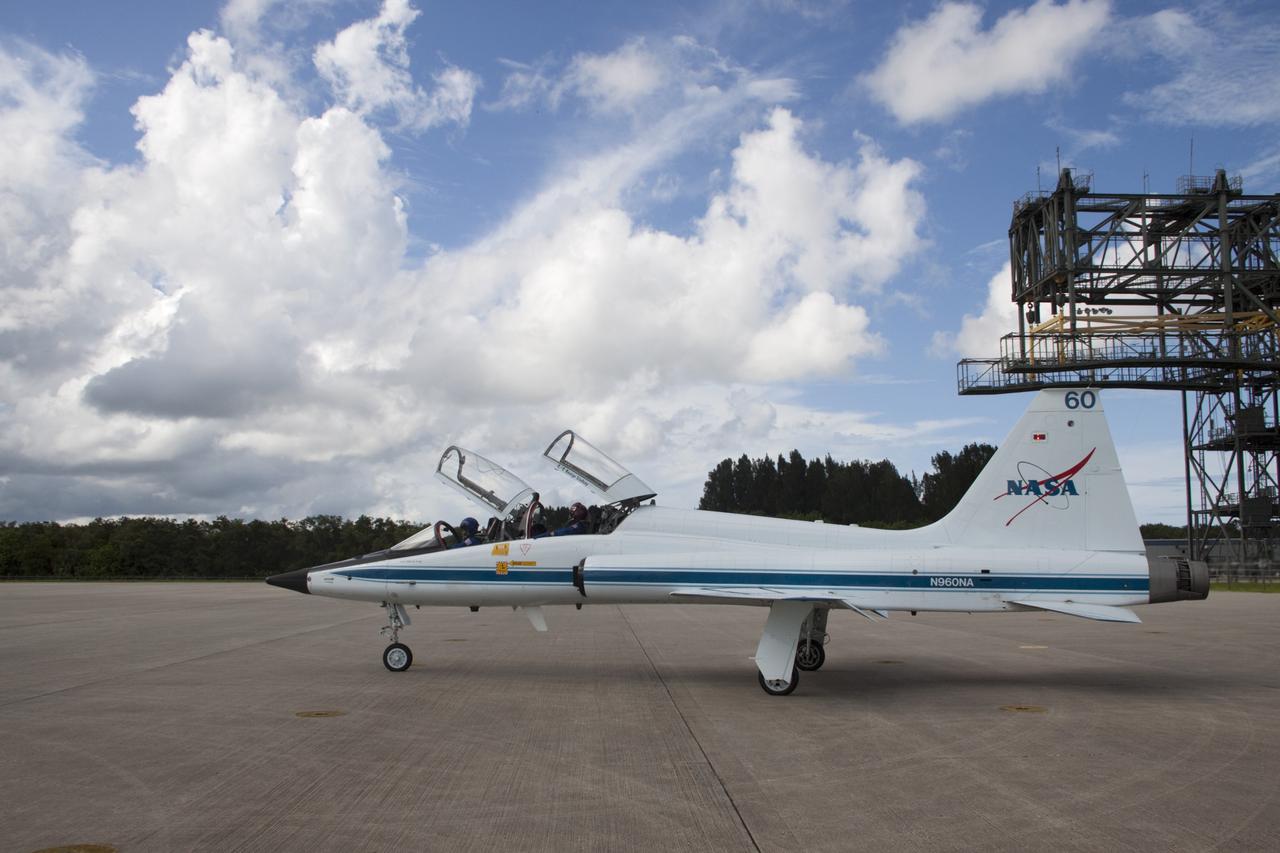 CAPE CANAVERAL, Fla. – At the Shuttle Landing Facility at NASA's Kennedy Space Center in Florida, STS-135 Pilot Doug Hurley and Mission Specialist Sandra Magnus (in the red helmet) prepare for departure in a T-38 training jet. The astronauts, along with Commander Chris Ferguson, were at the center for the traditional post-flight crew return presentation. To the left of the jet is the space shuttle's mate-demate device. STS-135 Mission Specialist Rex Walheim was unable to attend the Kennedy event. In July 2011, Atlantis and its crew delivered to the International Space Station the Raffaello multi-purpose logistics module packed with more than 9,400 pounds of spare parts, equipment and supplies that will sustain station operations for the next year. STS-135 was the 33rd and final flight for Atlantis and the final mission of the Space Shuttle Program. For more information, visit www.nasa.gov/mission_pages/shuttle/shuttlemissions/sts135/index.html. Photo credit: NASA/Jim Grossmann