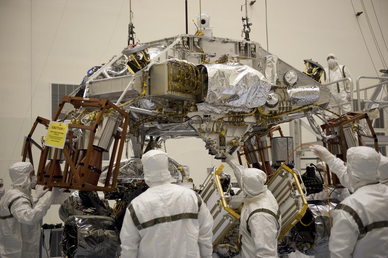 CAPE CANAVERAL, Fla. – Technicians at the Payload Hazardous Servicing Facility at NASA's Kennedy Space Center in Florida, guide an overhead crane as it lowers a rocket-powered descent stage over NASA's Mars Science Laboratory (MSL) rover, known as Curiosity, for integration. The descent stage will lower Curiosity to the surface of Mars.     A United Launch Alliance Atlas V-541 configuration will be used to loft MSL into space. Curiosity’s 10 science instruments are designed to search for evidence on whether Mars has had environments favorable to microbial life, including chemical ingredients for life.  The unique rover will use a laser to look inside rocks and release its gasses so that the rover’s spectrometer can analyze and send the data back to Earth. MSL is scheduled to launch Nov. 25 with a window extending to Dec. 18 and arrival at Mars Aug. 2012. For more information, visit http://www.nasa.gov/msl. Photo credit: NASA/Kim Shiflett