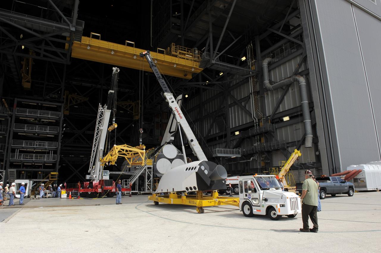 CAPE CANAVERAL, Fla. – In the Vehicle Assembly Building at NASA's Kennedy Space Center in Florida, workers, using overhead cranes, raise a cage which will be placed over an Approach and Landing Test Assembly (ALTA) pod (in the foreground). The ALTA pod will be lifted for attachment to space shuttle Endeavour on the site once housing the orbital maneuvering system (OMS) pod. The demonstration test is being conducted to ensure the center’s equipment will fit into the hangar at the National Air and Space Museum when installing an ALTA pod on shuttle Enterprise. The pod must be reinstalled on a shuttle for transport on a 747 carrier aircraft. The simulation also tests procedures and timelines necessary to carry out the process.       The work is part of the Space Shuttle Program’s transition and retirement processing. Enterprise, which was not equipped for space flight, was built as a test vehicle to demonstrate that the orbiter could fly in the atmosphere and land like an airplane. In 1985, Enterprise was ferried from the Kennedy Space Center to Dulles Airport, Washington, D.C., and became the property of the Smithsonian Institute. Enterprise will be moved from the Smithsonian Institution National Air and Space Museum's Steven F. Udvar-Hazy Center in Chantilly, Va., to the Intrepid Sea, Air and Space Museum in New York. For more information, visit http://www.nasa.gov/shuttle. Photo credit: NASA/Ken Shiflett