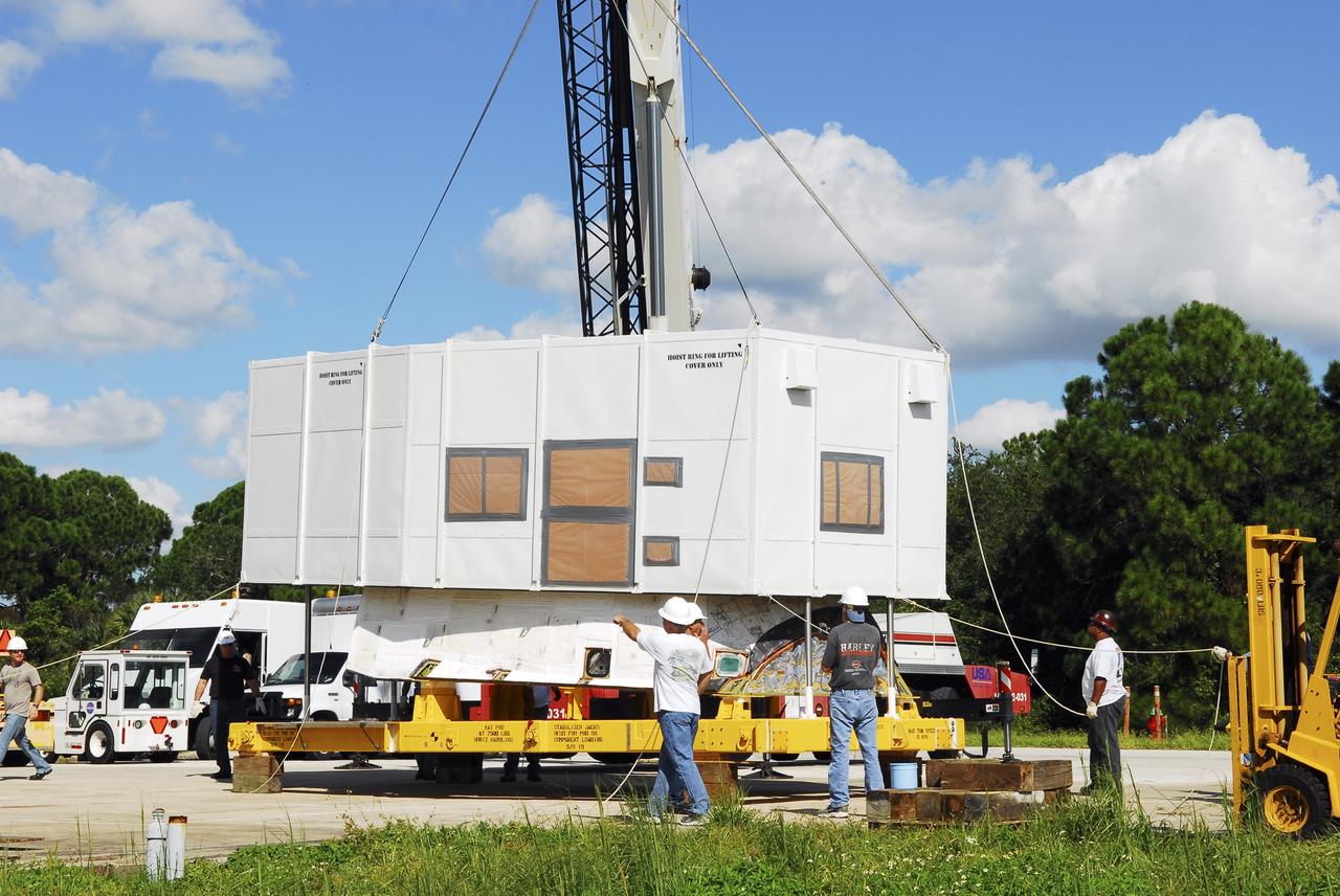 CAPE CANAVERAL, Fla. – Workers outside the Hypergol Maintenance Facility at NASA’s Kennedy Space Center in Florida use a crane to lift the shipping container off of space shuttle Discovery's orbital maneuvering system (OMS) pod. The OMS has been returned from White Sands Space Harbor in New Mexico where it underwent a complete deservicing and cleaning.        The work is part of the Space Shuttle Program’s transition and retirement processing of space shuttle Discovery. The shuttle will go to the Smithsonian's National Air and Space Museum, Steven F. Udvar-Hazy Center in Chantilly, Va. For more information, visit http://www.nasa.gov/shuttle. Photo credit: NASA/Jim Grossmann