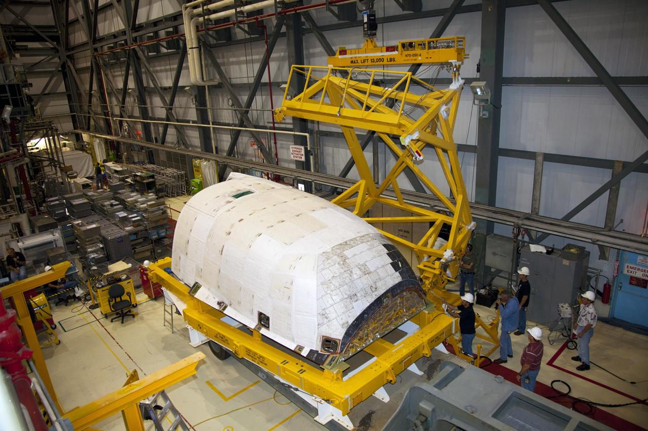 CAPE CANAVERAL, Fla. – At NASA’s Kennedy Space Center in Florida, a crane is lowered toward an orbital maneuvering system (OMS) pod that awaits installation on space shuttle Discovery in Orbiter Processing Facility-1.    The OMS pod was returned from White Sands Space Harbor in New Mexico where it underwent a complete deservicing and cleaning. The work is part of the Space Shuttle Program’s transition and retirement processing of space shuttle Discovery. The shuttle will go to the Smithsonian’s National Air and Space Museum, Steven F. Udvar-Hazy Center in Chantilly, Va., in April 2012. For more information, visit http://www.nasa.gov/shuttle.  Photo credit: NASA/Frankie Martin