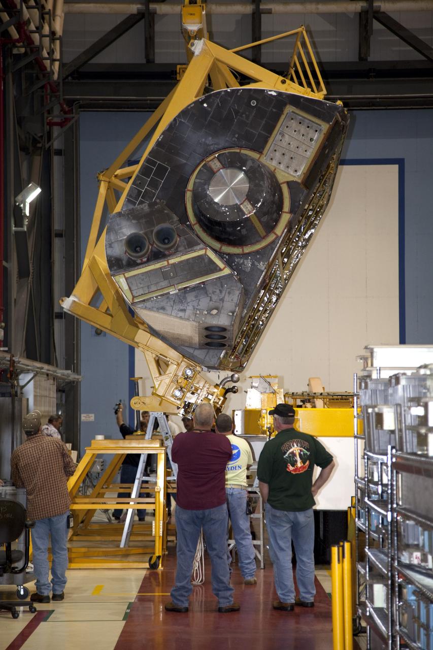 CAPE CANAVERAL, Fla. – In Orbiter Processing Facility-1 at NASA’s Kennedy Space Center in Florida, technicians monitor the progress as a crane is used to carry an orbital maneuvering system (OMS) pod that will be installed on space shuttle Discovery.      The OMS pod was returned from White Sands Space Harbor in New Mexico where it underwent a complete deservicing and cleaning. The work is part of the Space Shuttle Program’s transition and retirement processing of space shuttle Discovery. The shuttle will go to the Smithsonian’s National Air and Space Museum, Steven F. Udvar-Hazy Center in Chantilly, Va., in April 2012. For more information, visit http://www.nasa.gov/shuttle.  Photo credit: NASA/Frankie Martin