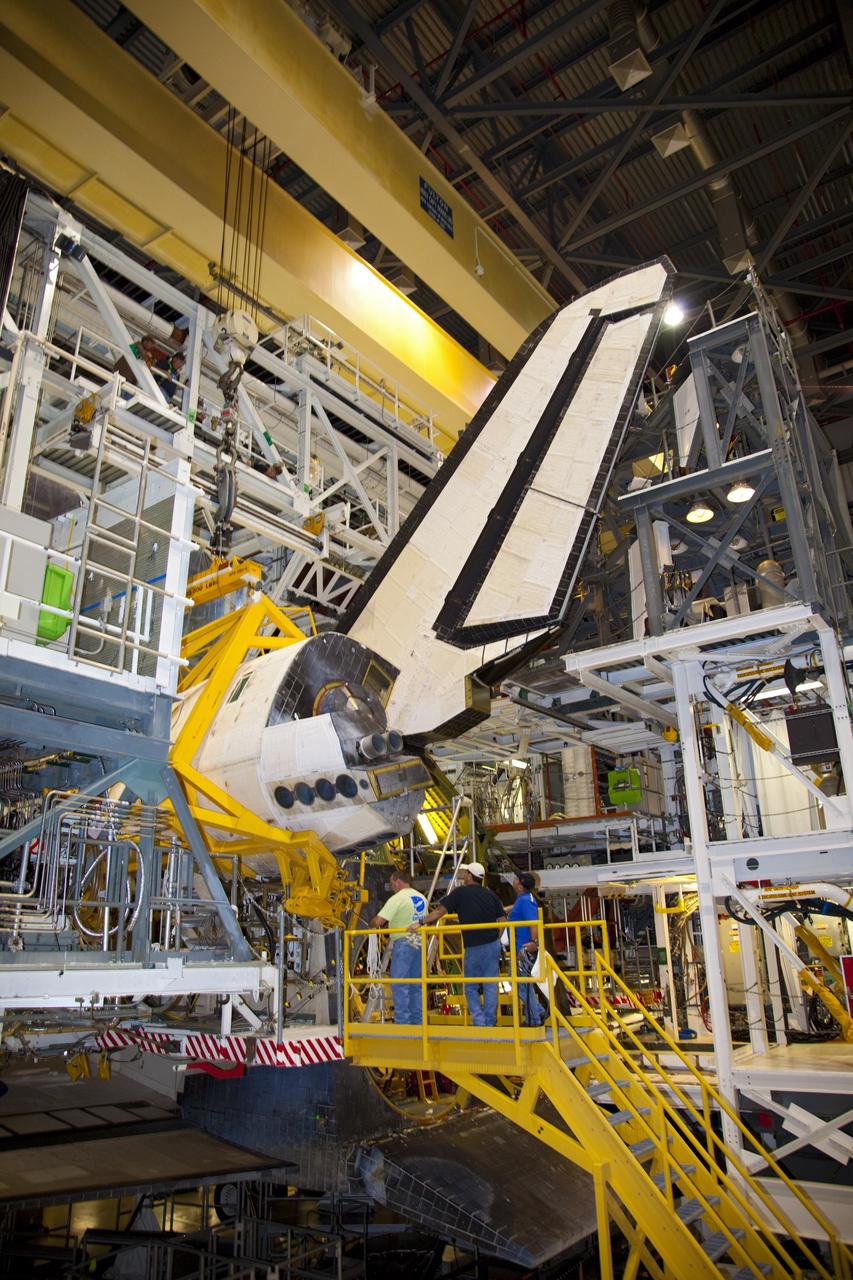 CAPE CANAVERAL, Fla. – In Orbiter Processing Facility-1 at NASA’s Kennedy Space Center in Florida, technicians monitor the progress as a crane lowers an orbital maneuvering system (OMS) pod closer for installation on space shuttle Discovery.      The OMS pod was returned from White Sands Space Harbor in New Mexico where it underwent a complete deservicing and cleaning. The work is part of the Space Shuttle Program’s transition and retirement processing of space shuttle Discovery. The shuttle will go to the Smithsonian’s National Air and Space Museum, Steven F. Udvar-Hazy Center in Chantilly, Va., in April 2012. For more information, visit http://www.nasa.gov/shuttle.  Photo credit: NASA/Frankie Martin