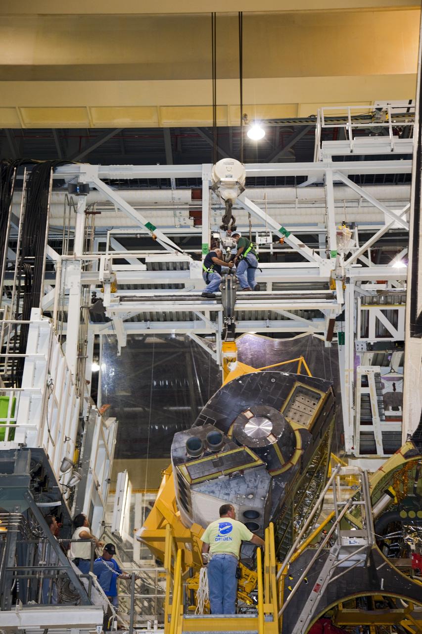 CAPE CANAVERAL, Fla. – In Orbiter Processing Facility-1 at NASA’s Kennedy Space Center in Florida, technicians assist as a crane lowers an orbital maneuvering system (OMS) pod for installation on space shuttle Discovery.    The OMS pod was returned from White Sands Space Harbor in New Mexico where it underwent a complete deservicing and cleaning. The work is part of the Space Shuttle Program’s transition and retirement processing of space shuttle Discovery. The shuttle will go to the Smithsonian’s National Air and Space Museum, Steven F. Udvar-Hazy Center in Chantilly, Va., in April 2012. For more information, visit http://www.nasa.gov/shuttle.  Photo credit: NASA/Frankie Martin