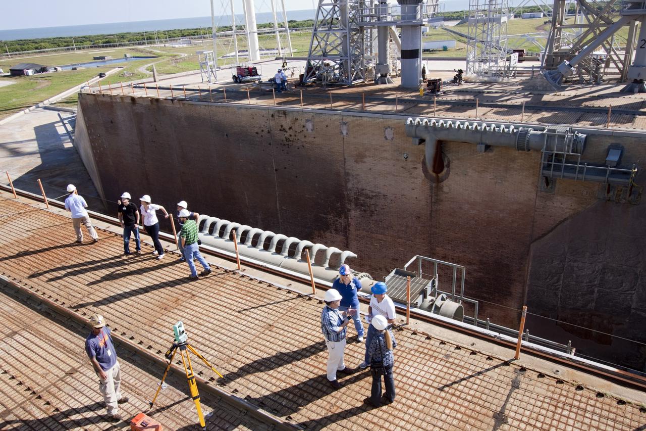 CAPE CANAVERAL, Fla. – Mechanical engineering students from Louisiana State University, the group on the left, joined engineers and scientists at Launch Pad 39B at NASA's Kennedy Space Center in Florida as the students toured the facility to have a look at the flame trench. Designers are looking for new, flame and vibration-resistant materials to line the trench. To help in the search, a team of mechanical engineering students at Louisiana State University are to build a scaled-down version of the flame trench that Kennedy's scientists can use to try out sample materials for the trench. If the samples work in the lab, they can be tried out in the real flame trenches at Launch Pad 39A and 39B.    The launch pad has been refurbished extensively and work is continuing to modify the pad to support a variety of launch vehicles in the future. Photo credit: NASA/Jim Grossmann