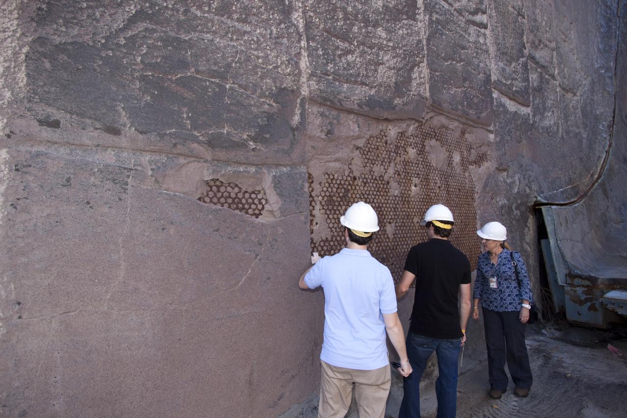 CAPE CANAVERAL, Fla. – Louisiana State University mechanical engineering students Kevin Schenker, from left, and Jacob Koch join Luz Marina Calle, a scientist at NASA's Kennedy Space in Florida, as they examine a portion of the wall of the flame trench at Launch Pad 39B. Designers are looking for new, flame and vibration-resistant materials to line the trench. To help in the search, a team of mechanical engineering students at Louisiana State University are to build a scaled-down version of the flame trench that Kennedy's scientists can use to try out sample materials for the trench. If the samples work in the lab, they can be tried out in the real flame trenches at Launch Pad 39A and 39B.    The launch pad has been refurbished extensively and work is continuing to modify the pad to support a variety of launch vehicles in the future. Photo credit: NASA/Jim Grossmann