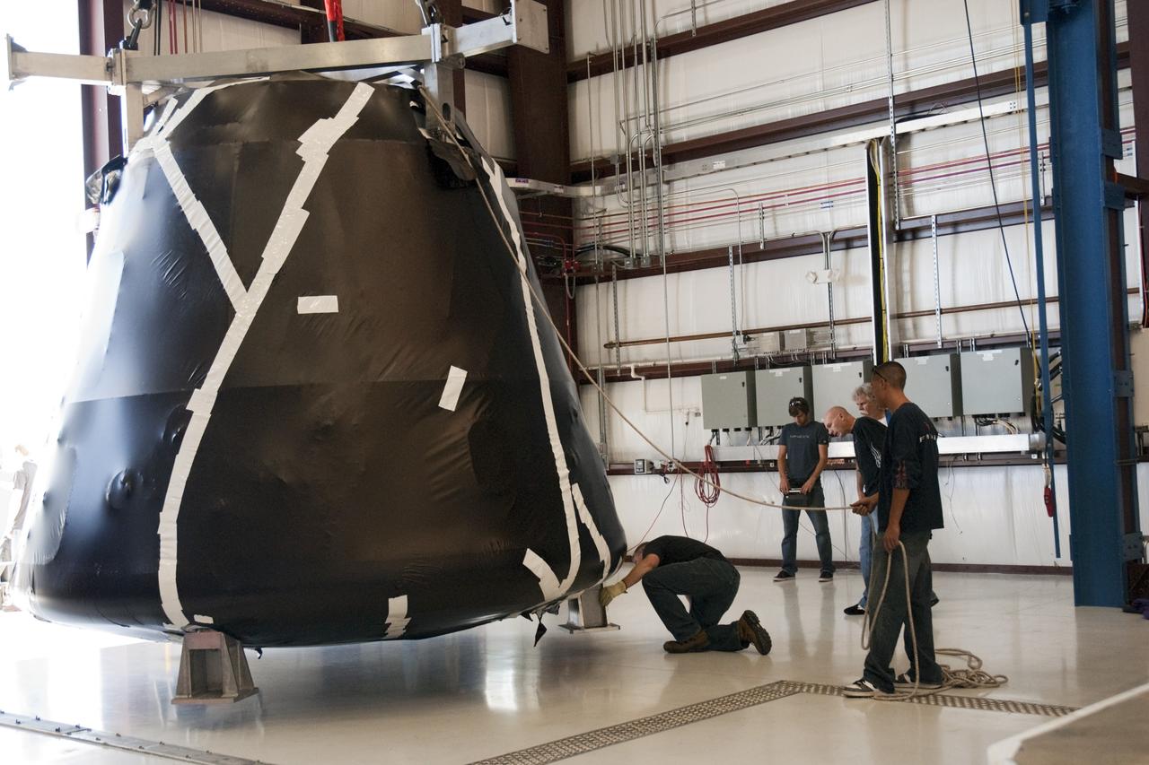 Workers lower the latest Space Exploration Technologies Corp. (SpaceX) Dragon capsule at Cape Canaveral Air Force Station in Florida on Oct. 23 so it can be processed and attached to the top of a Falcon 9 rocket on Space Launch Complex-40 for the company's next demonstration test flight for NASA's Commercial Orbital Transportation Services (COTS) program.    SpaceX is one of two companies under contract with NASA to take cargo to the International Space Station. NASA is working with SpaceX to combine its last two demonstration flights, and if approved, the Falcon 9 rocket would launch the Dragon capsule to the orbiting laboratory for a docking within the next several months. Photo credit: NASA/ Charisse Nahser
