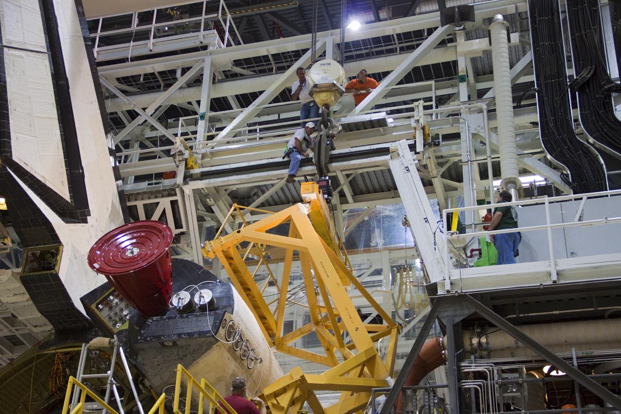 CAPE CANAVERAL, Fla. -- Inside Orbiter Processing Facility-2 at NASA’s Kennedy Space Center in Florida, technicians monitor the progress as a large crane lowers a sling toward space shuttle Atlantis’ right orbital maneuvering system (OMS) pod.      The work is part of the Space Shuttle Program’s transition and retirement processing of shuttle Atlantis. The OMS pod will be removed and sent to White Sands Space Harbor in New Mexico where it will undergo a complete deservicing and cleaning and then be returned to Kennedy for reinstallation on Atlantis. Atlantis is being prepared for display at the Kennedy Space Center Visitor Complex.  Photo credit: NASA/Jim Grossmann