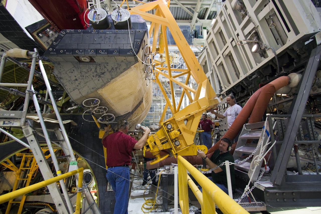 CAPE CANAVERAL, Fla. -- Inside Orbiter Processing Facility-2 at NASA’s Kennedy Space Center in Florida, technicians monitor the progress as a large crane lowers a sling that will be secured around space shuttle Atlantis’ right orbital maneuvering system (OMS) pod.    The work is part of the Space Shuttle Program’s transition and retirement processing of shuttle Atlantis. The OMS pod will be removed and sent to White Sands Space Harbor in New Mexico where it will undergo a complete deservicing and cleaning and then be returned to Kennedy for reinstallation on Atlantis. Atlantis is being prepared for display at the Kennedy Space Center Visitor Complex.  Photo credit: NASA/Jim Grossmann