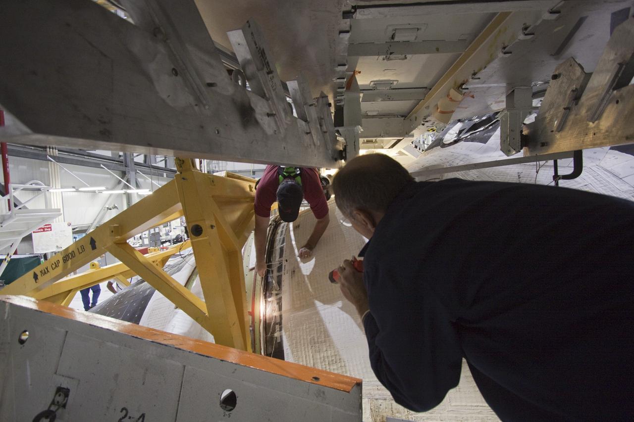 CAPE CANAVERAL, Fla. -- Inside Orbiter Processing Facility-1 at NASA’s Kennedy Space Center in Florida, technicians assist with the installation of the forward reaction control system (FRCS) on space shuttle Discovery.    The FRCS was returned from White Sands Space Harbor in New Mexico where it underwent a complete deservicing and cleaning. The work is part of the Space Shuttle Program’s transition and retirement processing of shuttle Discovery. Discovery is being prepared for display at Smithsonian’s National Air and Space Museum, Steven F. Udvar-Hazy Center in Chantilly, Va. For more information, visit http://www.nasa.gov/shuttle.  Photo credit: NASA/Jim Grossmann