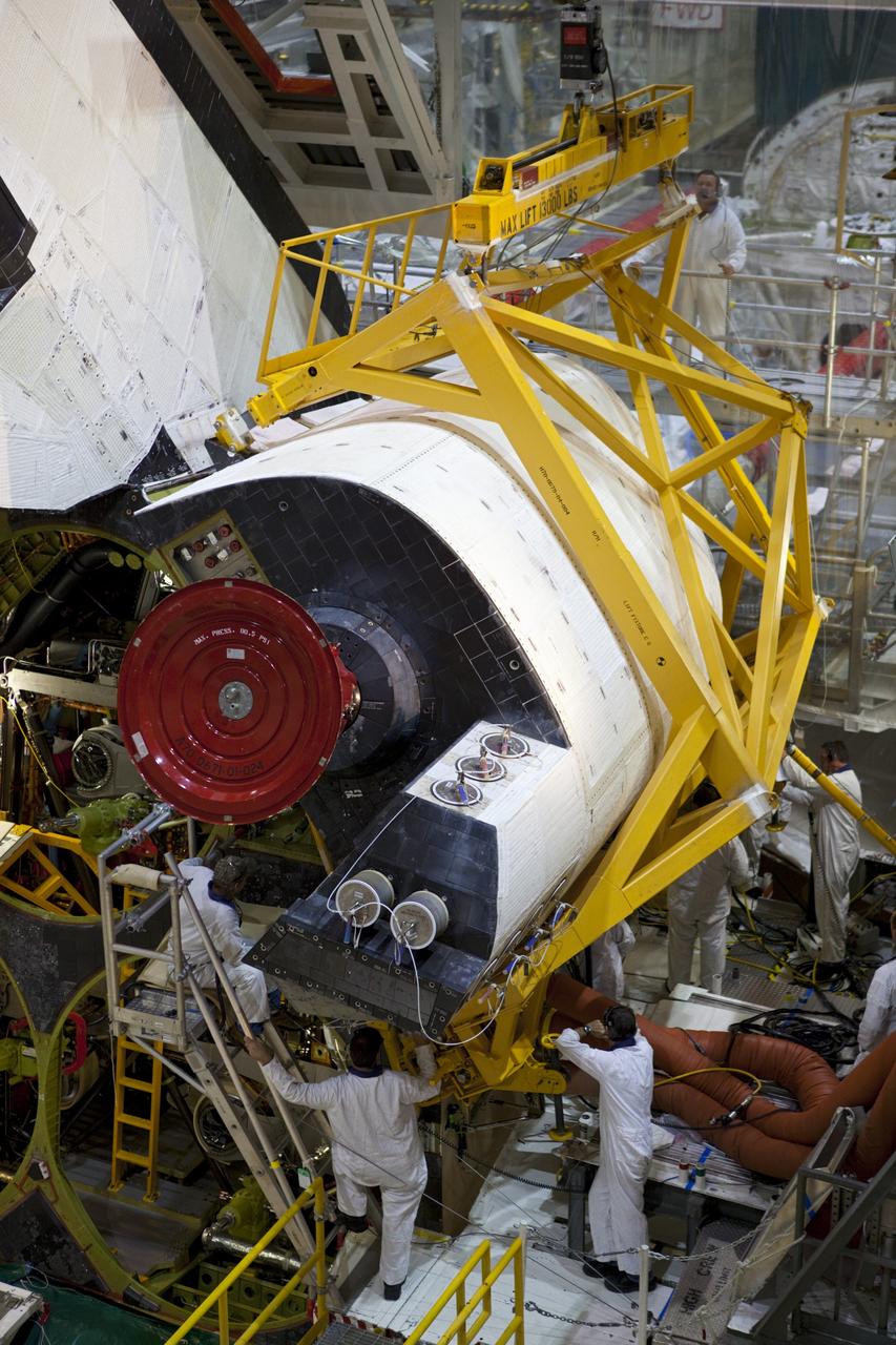 CAPE CANAVERAL, Fla. -- Inside Orbiter Processing Facility-2 at NASA’s Kennedy Space Center in Florida, technicians help secure a sling around space shuttle Atlantis’ right orbital maneuvering system (OMS) pod and prepare it for removal.    The work is part of the Space Shuttle Program’s transition and retirement processing of shuttle Atlantis. The OMS pod will be removed and sent to White Sands Space Harbor in New Mexico where it will undergo a complete deservicing and cleaning and then be returned to Kennedy for reinstallation on Atlantis. Atlantis is being prepared for display at the Kennedy Space Center Visitor Complex.  Photo credit: NASA/Dimitri Gerondidakis