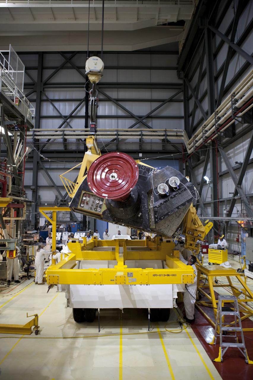 CAPE CANAVERAL, Fla. – Inside Orbiter Processing Facility-2 at NASA’s Kennedy Space Center in Florida, technicians monitor the progress as a large crane lowers space shuttle Atlantis’ right orbital maneuvering system (OMS) pod onto a pallet.    The work is part of the Space Shuttle Program’s transition and retirement processing of shuttle Atlantis. Both OMS pods will be removed and sent to White Sands Space Harbor in New Mexico where they will undergo a complete deservicing and cleaning and then be returned to Kennedy for reinstallation on Atlantis. Atlantis is being prepared for display at the Kennedy Space Center Visitor Complex.  Photo credit: NASA/Dimitri Gerondidakis