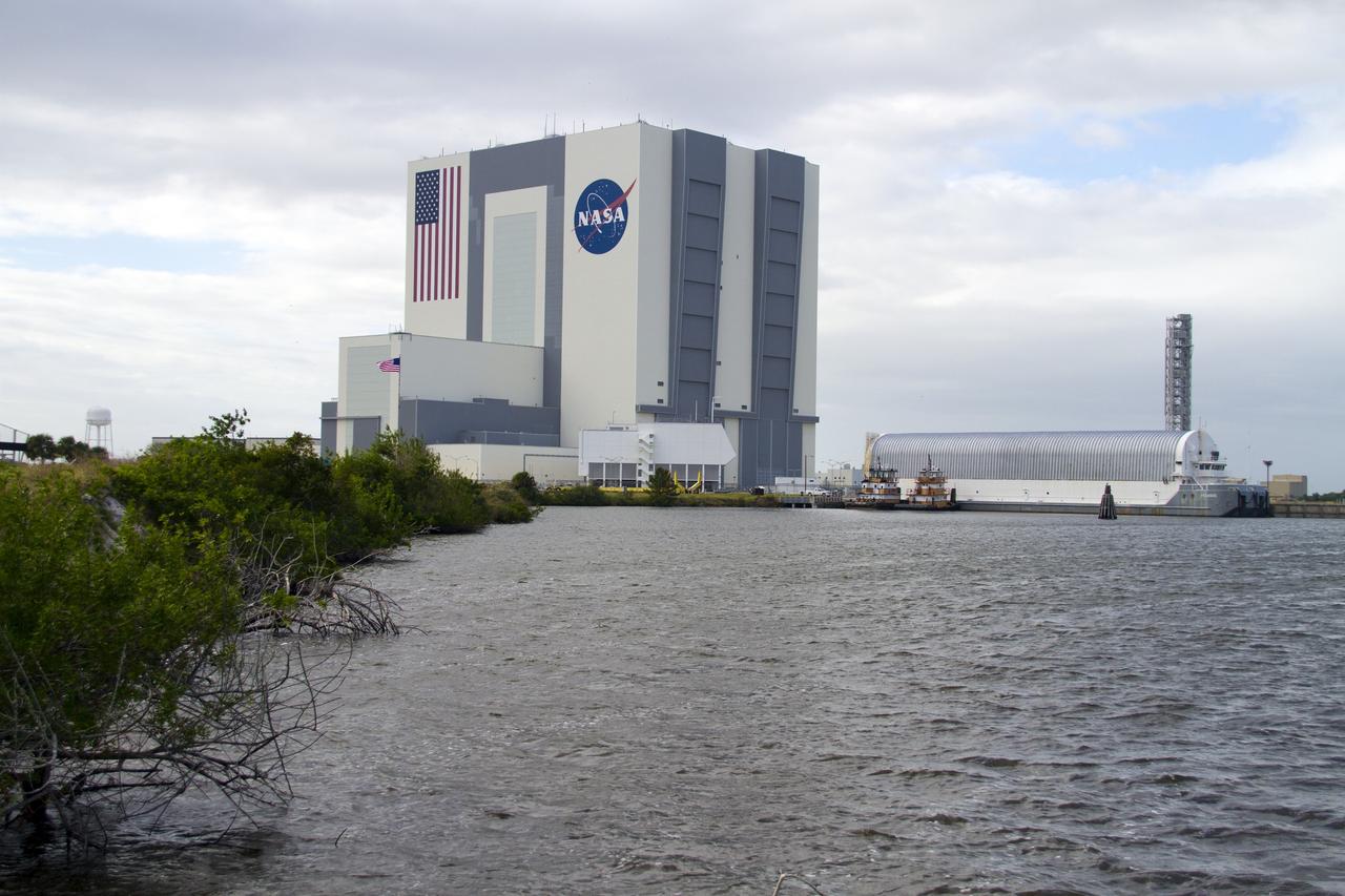 CAPE CANAVERAL, Fla. – The Vehicle Assembly Building towers over two tugboats sitting alongside the Pegasus Barge which is moored in a secure area of the Turn Basin in the Launch Complex 39 area at NASA's Kennedy Space Center in Florida. The 266-foot-long and 50-foot-wide barge will be towed to Stennis by NASA's Freedom Star ship. Since being delivered to NASA in 1999, Pegasus sailed 41 times and transported 31 shuttle external fuel tanks from Michoud Assembly Facility near New Orleans to Kennedy.    The barge will leave Kennedy, perhaps for the final time. Both the barge and shuttle equipment will remain in storage until their specific future uses are determined. The SSMEs themselves will be transported to Stennis separately for use with the agency’s new heavy-lift rocket, the Space Launch System. The work is part of the Space Shuttle Program’s transition and retirement processing. For more information about Shuttle Transition and Retirement, visit http://www.nasa.gov/mission_pages/transition/home/index.html. Photo credit: NASA/Cory Huston