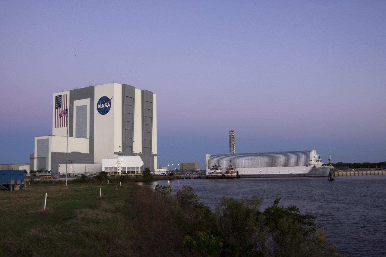 CAPE CANAVERAL, Fla. – The Vehicle Assembly Building towers over two tugboats and the Pegasus Barge moored in a secure area of the Turn Basin in the Launch Complex 39 area at NASA's Kennedy Space Center in Florida. The 266-foot-long and 50-foot-wide barge will be towed by NASA's Freedom Star ship to deliver space shuttle main engine (SSME) ground support equipment to Stennis Space Center near Bay St. Louis, Miss. Since being delivered to NASA in 1999, Pegasus sailed 41 times and transported 31 shuttle external fuel tanks from Michoud Assembly Facility near New Orleans to Kennedy. The barge will leave Kennedy, perhaps for the final time. Both the barge and shuttle equipment will remain in storage until their specific future uses are determined. The SSMEs themselves will be transported to Stennis separately for use with the agency’s new heavy-lift rocket, the Space Launch System. The work is part of the Space Shuttle Program’s transition and retirement processing. For more information about Shuttle Transition and Retirement, visit http://www.nasa.gov/mission_pages/transition/home/index.html. Photo credit: NASA/ Kim Shiflett