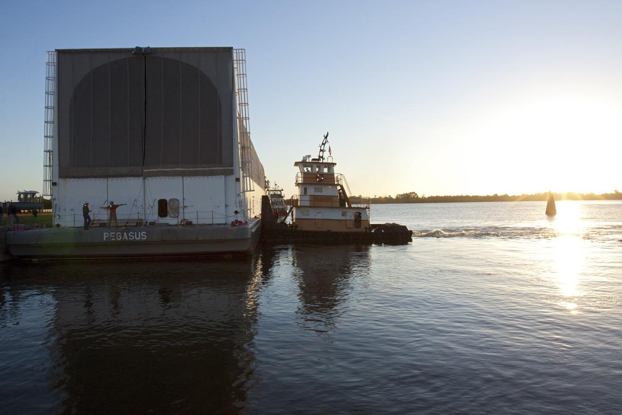 CAPE CANAVERAL, Fla. – In the early morning light at the Turn Basin in the Launch Complex 39 area at NASA's Kennedy Space Center in Florida, a tugboat begins to position the Pegasus Barge for towing. The 266 ft long and 50 ft wide barge will be towed by NASA's Freedom Star ship to deliver space shuttle main engine (SSME) ground support equipment to Stennis Space Center near Bay St. Louis, Miss. Since being delivered to NASA in 1999, Pegasus sailed 41 times and transported 31 shuttle external fuel tanks from Michoud Assembly Facility near New Orleans to Kennedy. The barge will leave Kennedy, perhaps for the final time. Both the barge and shuttle equipment will remain in storage until their specific future uses are determined. The SSMEs themselves will be transported to Stennis separately for use with the agency’s new heavy-lift rocket, the Space Launch System. The work is part of the Space Shuttle Program’s transition and retirement processing. For more information about Shuttle Transition and Retirement, visit http://www.nasa.gov/mission_pages/transition/home/index.html. Photo credit: NASA/ Kim Shiflett