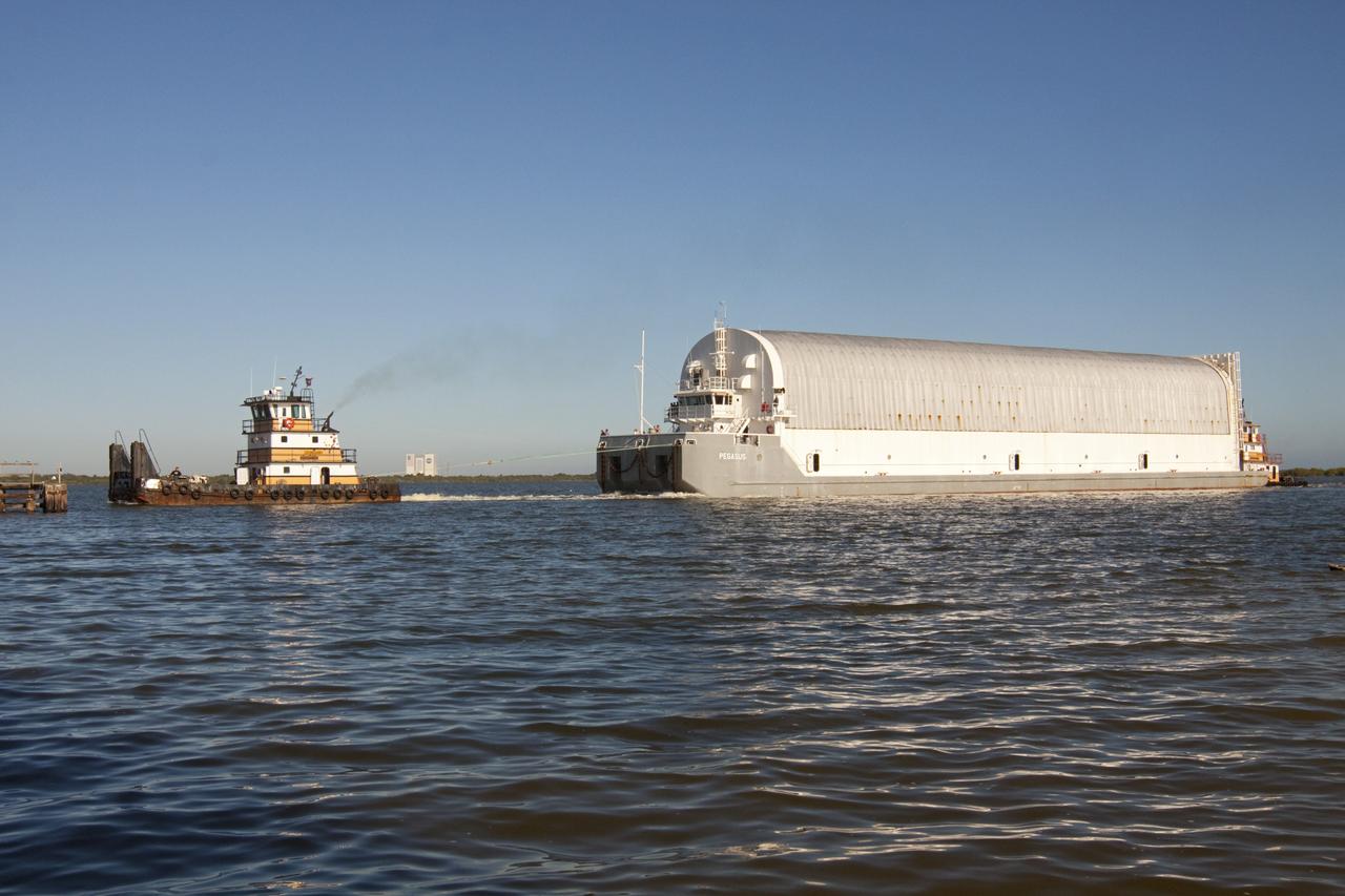 CAPE CANAVERAL, Fla. – A tugboat pulls the Pegasus Barge through the Banana River after leaving NASA's Kennedy Space Center in Florida. The 266-foot-long and 50-foot-wide barge will be towed by NASA's Freedom Star ship to deliver space shuttle main engine (SSME) ground support equipment to Stennis Space Center near Bay St. Louis, Miss. Since being delivered to NASA in 1999, Pegasus sailed 41 times and transported 31 shuttle external fuel tanks from Michoud Assembly Facility near New Orleans to Kennedy. To the right of the tugboat in the background is the Vehicle Assembly Building. The barge is leaving Kennedy, perhaps for the final time. Both the barge and shuttle equipment will remain in storage until their specific future uses are determined. The SSMEs themselves will be transported to Stennis separately for use with the agency's new heavy-lift rocket, the Space Launch System. The work is part of the Space Shuttle Program’s transition and retirement processing. For more information about Shuttle Transition and Retirement, visit http://www.nasa.gov/mission_pages/transition/home/index.html. Photo credit: NASA/Kim Shiflett