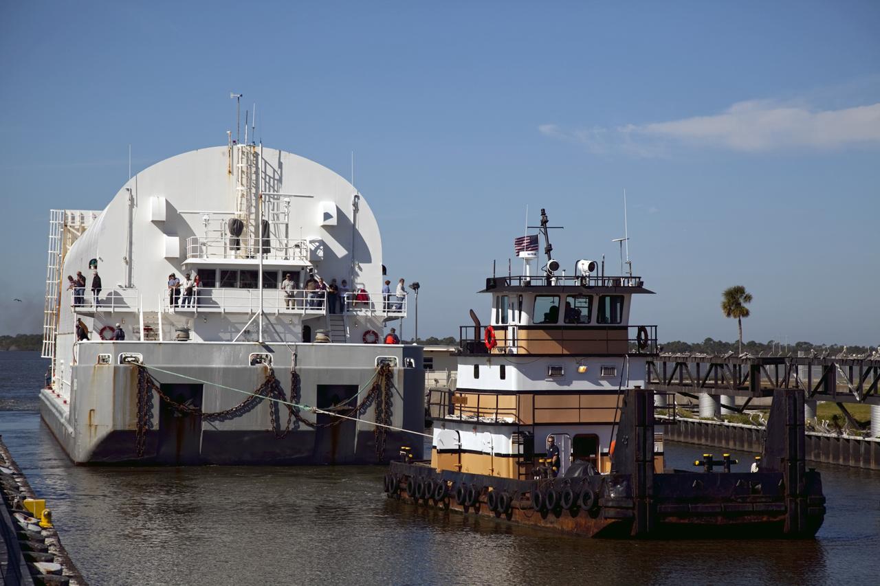 CAPE CANAVERAL, Fla. – Workers monitor the progress as a tugboat pulls NASA's Pegasus Barge through the Port Canaveral lock in Florida. The 266-foot-long and 50-foot-wide barge will be towed by NASA's Freedom Star ship to deliver space shuttle main engine (SSME) ground support equipment to Stennis Space Center near Bay St. Louis, Miss. Since being delivered to NASA in 1999, Pegasus sailed 41 times and transported 31 shuttle external fuel tanks from Michoud Assembly Facility near New Orleans to Kennedy Space Center. The barge is leaving Kennedy, perhaps for the final time. Both the barge and shuttle equipment will remain in storage until their specific future uses are determined. The SSMEs themselves will be transported to Stennis separately for use with the agency's new heavy-lift rocket, the Space Launch System. The work is part of the Space Shuttle Program’s transition and retirement processing. For more information about Shuttle Transition and Retirement, visit http://www.nasa.gov/mission_pages/transition/home/index.html. Photo credit: NASA/Frankie Martin