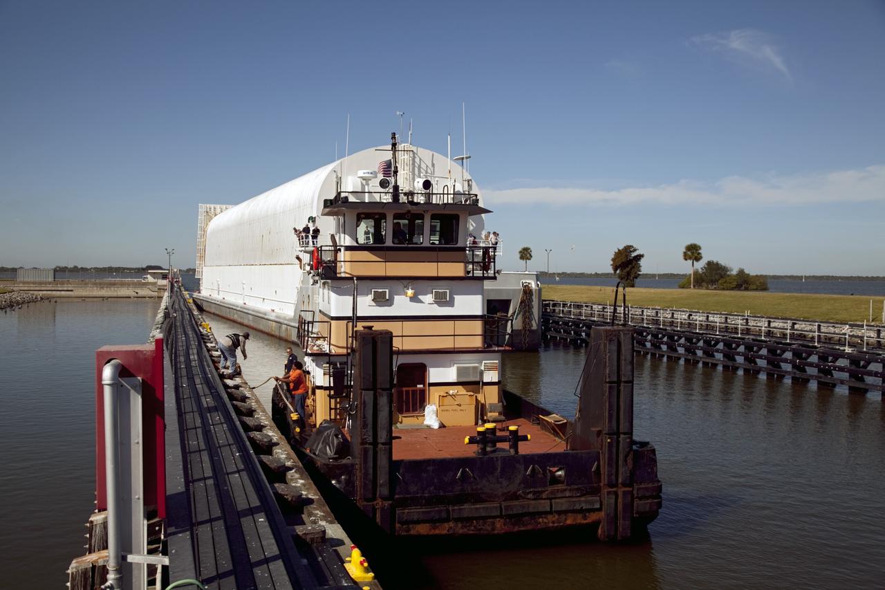 CAPE CANAVERAL, Fla. – A tugboat pulls alongside the dock as NASA's Pegasus Barge makes its way through the Port Canaveral lock in Florida. The 266-foot-long and 50-foot-wide barge will be towed by NASA's Freedom Star ship to deliver space shuttle main engine (SSME) ground support equipment to Stennis Space Center near Bay St. Louis, Miss. Since being delivered to NASA in 1999, Pegasus sailed 41 times and transported 31 shuttle external fuel tanks from Michoud Assembly Facility near New Orleans to Kennedy Space Center. The barge is leaving Kennedy, perhaps for the final time. Both the barge and shuttle equipment will remain in storage until their specific future uses are determined. The SSMEs themselves will be transported to Stennis separately for use with the agency's new heavy-lift rocket, the Space Launch System. The work is part of the Space Shuttle Program’s transition and retirement processing. For more information about Shuttle Transition and Retirement, visit http://www.nasa.gov/mission_pages/transition/home/index.html. Photo credit: NASA/Frankie Martin