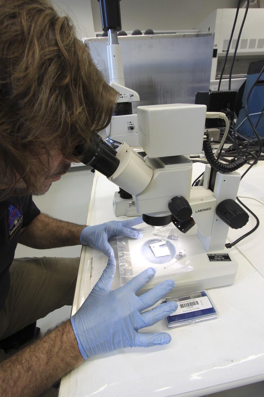 CAPE CANAVERAL, Fla. – In the Granular Mechanics and Regolith Operations (GMRO) Lab at NASA's Kennedy Space Center in Florida, Dr. Philip Metzger examines under a microscope a piece of the Surveyor 3 spacecraft returned from the lunar surface on the Apollo 12 mission.    The GMRO Lab is one of several labs located in NASA's Space Life Sciences Laboratory (SLSL) facility. The lab is staffed by three physicists, six mechanical or aerospace engineers and several technicians who are studying how the rocket exhaust of landing vehicles affects lunar and Martian science missions, including the sandblasting of instruments with soil and dust ejecta and the disturbance or contamination of soil beneath the lander.  For more information on the GMRO Lab, see p. 7 of the Spaceport News dated Nov. 11, 2011, at http://www.nasa.gov/centers/kennedy/pdf/603285main_nov11-2011.pdf.  Photo credit: NASA/Jim Grossmann