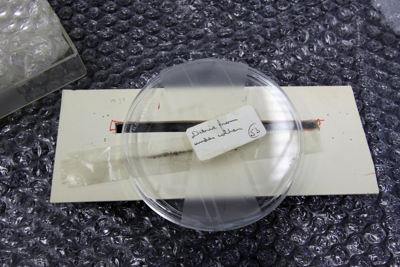 CAPE CANAVERAL, Fla. – In the Granular Mechanics and Regolith Operations (GMRO) Lab at NASA's Kennedy Space Center in Florida, a piece of the Surveyor 3 spacecraft returned from the lunar surface on the Apollo 12 mission is available for examination by the lab's staff.    The GMRO Lab is one of several labs located in NASA's Space Life Sciences Laboratory (SLSL) facility. The lab is staffed by three physicists, six mechanical or aerospace engineers and several technicians who are studying how the rocket exhaust of landing vehicles affects lunar and Martian science missions, including the sandblasting of instruments with soil and dust ejecta and the disturbance or contamination of soil beneath the lander.  For more information on the GMRO Lab, see p. 7 of the Spaceport News dated Nov. 11, 2011, at http://www.nasa.gov/centers/kennedy/pdf/603285main_nov11-2011.pdf.  Photo credit: NASA/Jim Grossmann