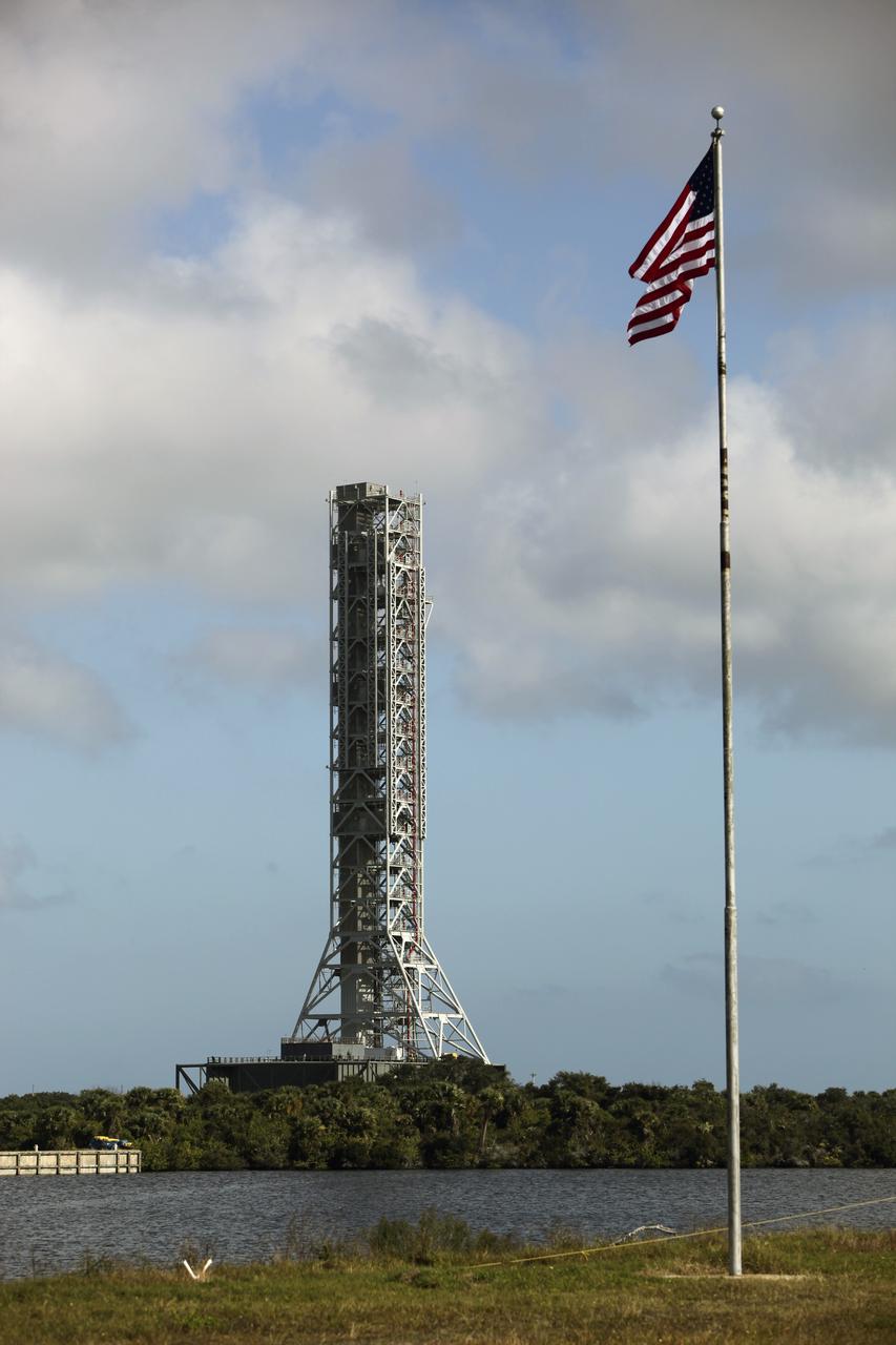 CAPE CANAVERAL, Fla. – As the American flag waves in the foreground at NASA’s Kennedy Space Center in Florida, the mobile launcher (ML) rolls out aboard a crawler-transporter from next to Kennedy's Vehicle Assembly Building to Launch Pad 39B, a distance of 4.2 miles. Data on the ML will be collected from structural and functional engineering tests and used for the next phases of construction. The 355-foot-tall ML structure, which took about two years to construct, is being modified to support NASA’s Space Launch System (SLS), the heavy-lift rocket that will launch astronauts farther into space than ever before. SLS will also create high-quality jobs here at home, and provide the cornerstone for America's future human space exploration efforts. Photo credit: NASA/Dimitri Gerondidakis