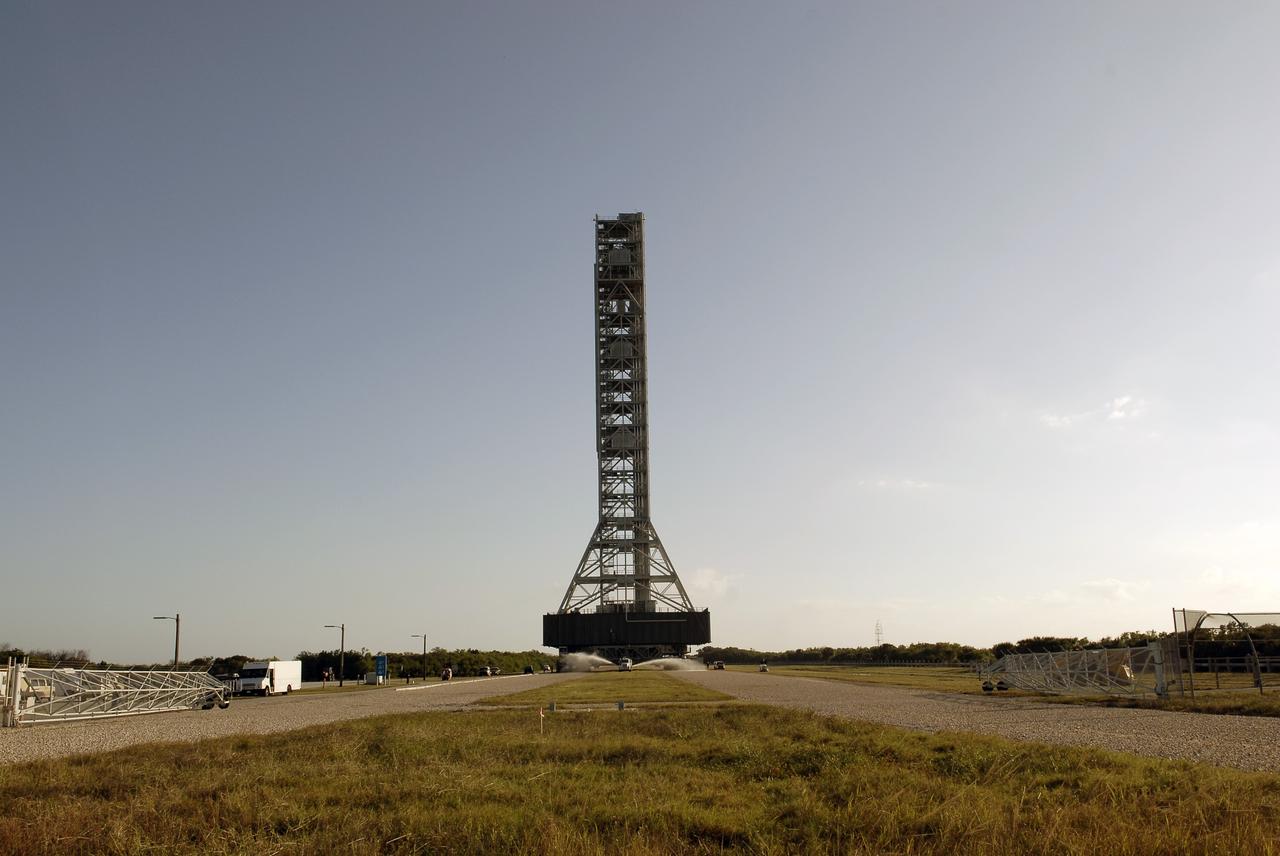 CAPE CANAVERAL, Fla. – A water truck leads the way, spraying water on the dry crawlerway to reduce dust particles in the air at NASA's Kennedy Space Center in Florida, as the mobile launcher (ML) rolls out aboard a crawler-transporter from next to Kennedy's Vehicle Assembly Building to Launch Pad 39B, a distance of 4.2 miles. Rollout began at about 9:15 a.m. EST. Data on the ML will be collected from structural and functional engineering tests and used for the next phases of construction overseen by NASA’s 21st Century Ground Systems Program. The 355-foot-tall ML structure, which took about two years to construct, is being modified to support NASA’s Space Launch System (SLS), the heavy-lift rocket that will launch astronauts farther into space than ever before. SLS will also create high-quality jobs here at home, and provide the cornerstone for America's future human space exploration efforts. Photo credit: NASA/Charisse Nahser