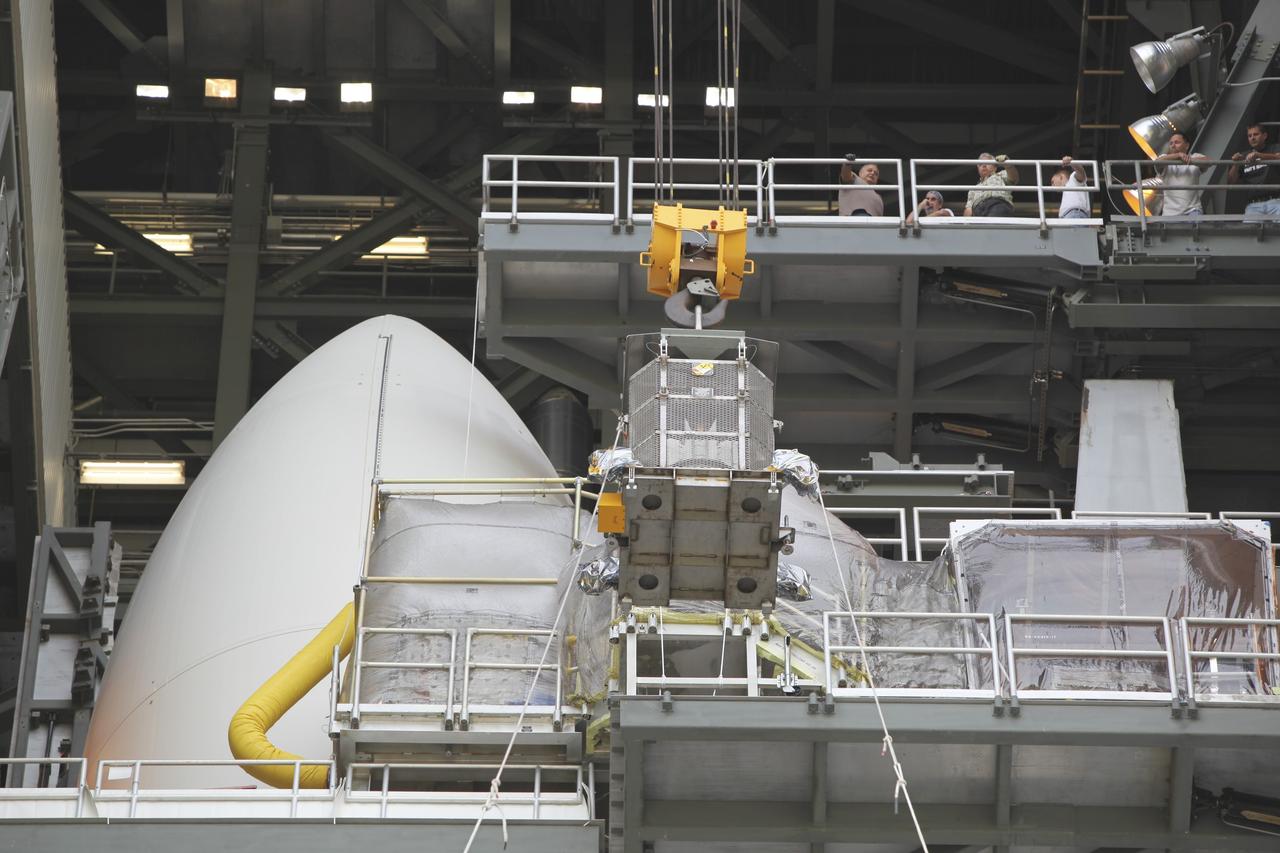 CAPE CANAVERAL, Fla. -- Employees gathered one level above monitor the progress of the protective mesh container known as the "gorilla cage," holding the multi-mission radioisotope thermoelectric generator (MMRTG) for NASA's Mars Science Laboratory (MSL) mission, as it is lifted near the top of the Atlas V rocket in the Vertical Integration Facility at Space Launch Complex 41. The generator will be installed on the MSL spacecraft, encapsulated within the payload fairing.    The MMRTG will generate the power needed for the mission from the natural decay of plutonium-238, a non-weapons-grade form of the radioisotope. Heat produced by this natural decay will provide constant power through the day and night during all seasons. MSL's components include a car-sized rover, Curiosity, which has 10 science instruments designed to search for signs of life, including methane, and help determine if the gas is from a biological or geological source. Heat emitted by the MMRTG will be circulated throughout the rover system to keep instruments, computers, mechanical devices and communications systems within their operating temperature ranges. Launch of MSL aboard a United Launch Alliance Atlas V rocket is targeted for Nov. 25 from Space Launch Complex 41 on Cape Canaveral Air Force Station. For more information, visit http://www.nasa.gov/msl. Photo credit: NASA/Dimitri Gerondidakis