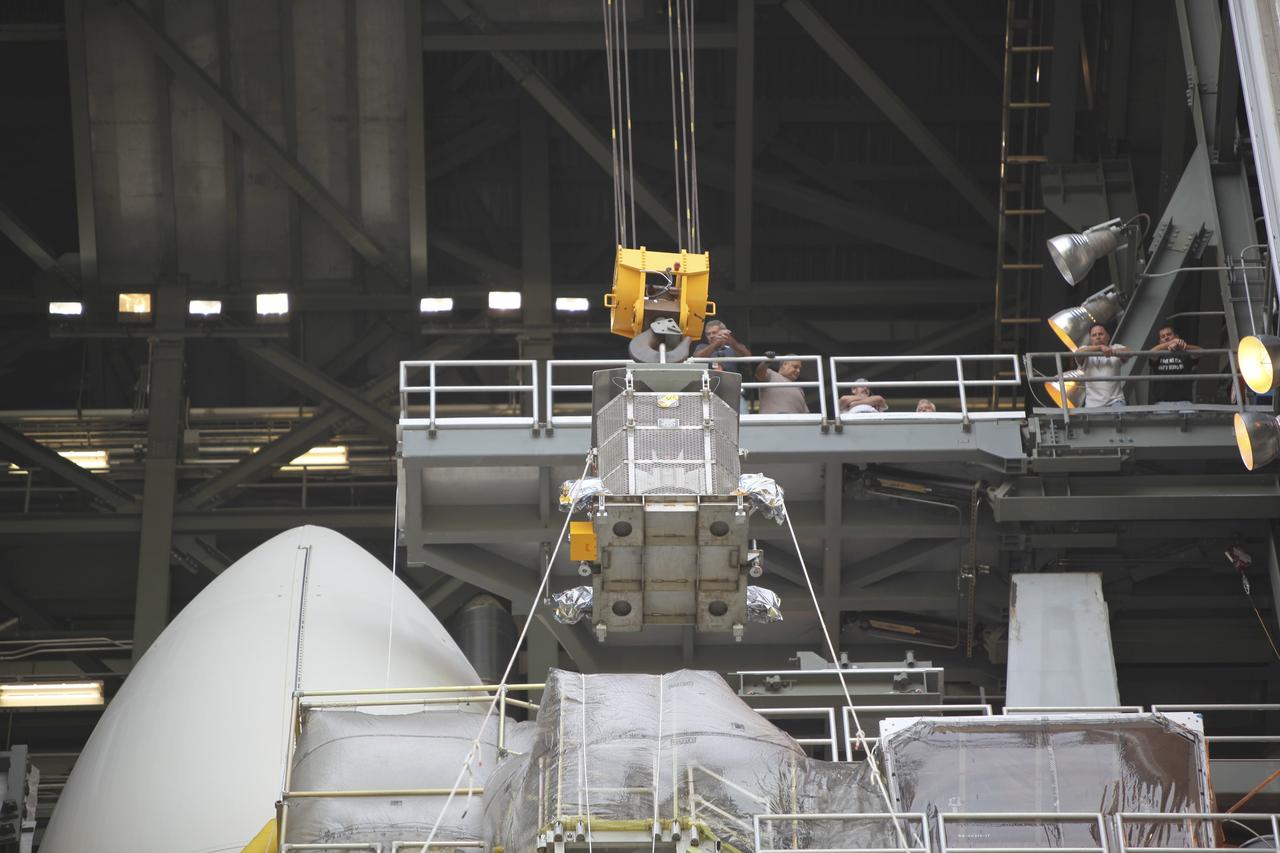 CAPE CANAVERAL, Fla. -- Employees monitor the progress of the protective mesh container known as the "gorilla cage," holding the multi-mission radioisotope thermoelectric generator (MMRTG) for NASA's Mars Science Laboratory (MSL) mission, as it is lifted near the top of the Atlas V rocket in the Vertical Integration Facility at Space Launch Complex 41. The MMRTG will be installed on the MSL spacecraft, encapsulated within the payload fairing.    The MMRTG will generate the power needed for the mission from the natural decay of plutonium-238, a non-weapons-grade form of the radioisotope. Heat emitted by this natural decay will provide constant power through the day and night during all seasons. MSL's components include a car-sized rover, Curiosity, which has 10 science instruments designed to search for signs of life, including methane, and help determine if the gas is from a biological or geological source. Heat emitted by the MMRTG will be circulated throughout the rover system to keep instruments, computers, mechanical devices and communications systems within their operating temperature ranges. Launch of MSL aboard a United Launch Alliance Atlas V rocket is targeted for Nov. 25 from Space Launch Complex 41 on Cape Canaveral Air Force Station. For more information, visit http://www.nasa.gov/msl. Photo credit: NASA/Dimitri Gerondidakis