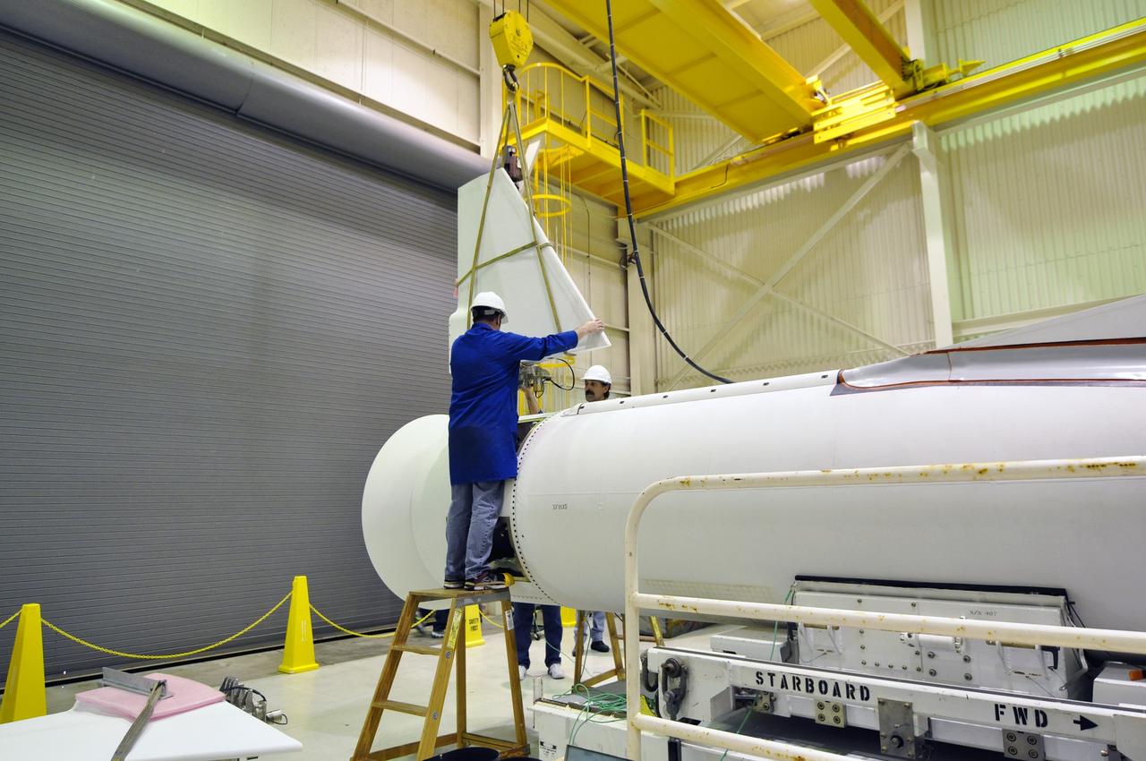 VANDENBERG AIR FORCE BASE, Calif. -- Inside a Pegasus booster processing facility at Vandenberg Air Force Base in California, an overhead crane lifts the first of the fins for the aft end of the Pegasus XL rocket's first stage as technicians guide it into place for installation.        The Orbital Sciences Corp. Pegasus rocket will launch the Nuclear Spectroscopic Telescope Array (NuSTAR) into space. After the rocket and spacecraft are processed at Vandenberg, they will be flown on the Orbital Sciences’ L-1011 carrier aircraft to the Ronald Reagan Ballistic Missile Defense Test Site at the Pacific Ocean’s Kwajalein Atoll for launch. The high-energy x-ray telescope will conduct a census for black holes, map radioactive material in young supernovae remnants, and study the origins of cosmic rays and the extreme physics around collapsed stars. For more information, visit science.nasa.gov/missions/nustar/. Photo credit: NASA/Randy Beaudoin, VAFB