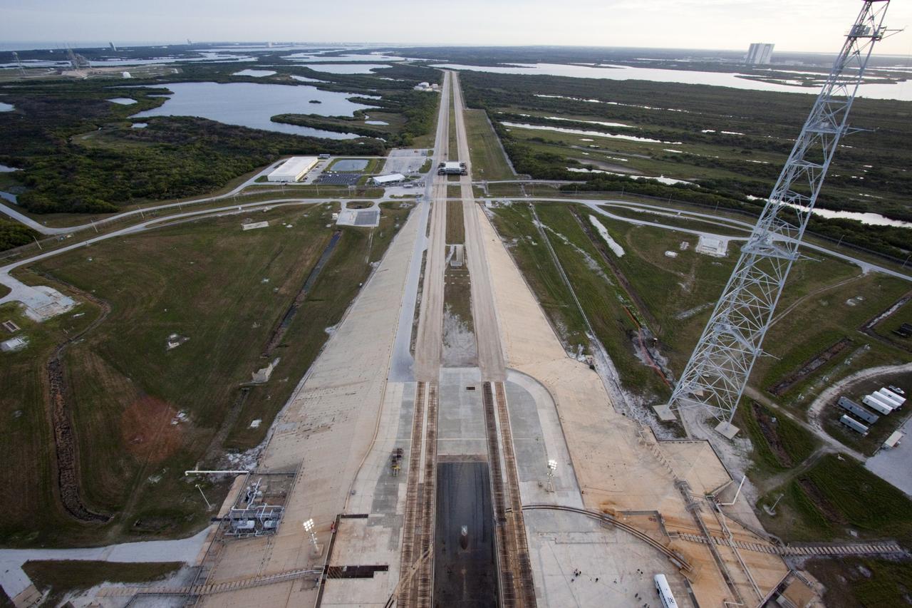 CAPE CANAVERAL, Fla. – At NASA Kennedy Space Center in Florida, this view, taken from the top of the 355-foot-tall mobile launcher at Launch Pad 39B, captures the crawler-transporter parked on the crawlerway leading to the pad's surface and the Vehicle Assembly Building (VAB), in the background at right. Media representatives are taking the 21st Century Ground Systems tour which also includes the VAB, a crawler-transporter, and the Launch Control Center's Firing Room 1. These facilities and equipment will be used to prepare and launch NASA's new Orion spacecraft on the Space Launch System heavy-lift rocket. The tour was arranged as part of prelaunch media activities for the agency's Mars Science Laboratory (MSL) launch. Liftoff of MSL aboard a United Launch Alliance Atlas V rocket from Space Launch Complex-41 on Cape Canaveral Air Force Station is planned during a launch window which extends from 10:02 a.m. to 11:45 a.m. EST on Nov. 26. For more information, visit http://www.nasa.gov/msl. Photo credit: NASA/Jim Grossmann